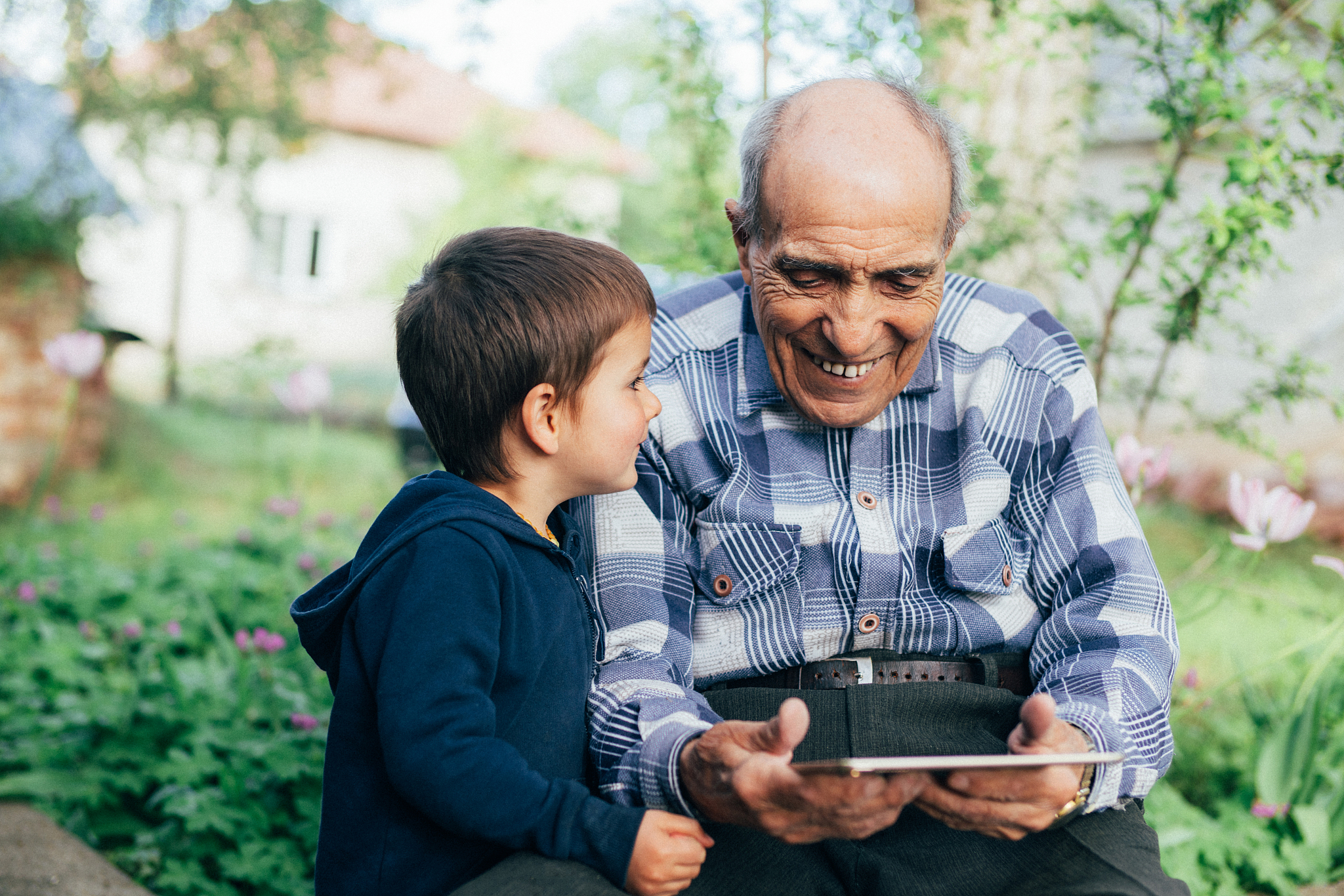 senior man watching videos on tablet with his great grandson