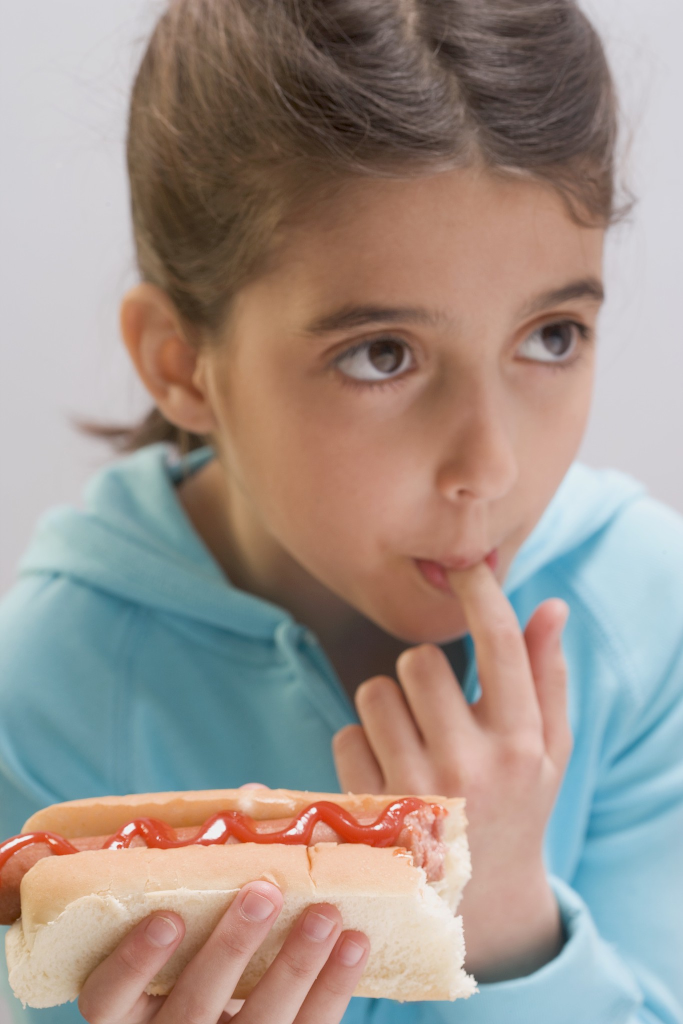 little girl eating hot dog with ketchup