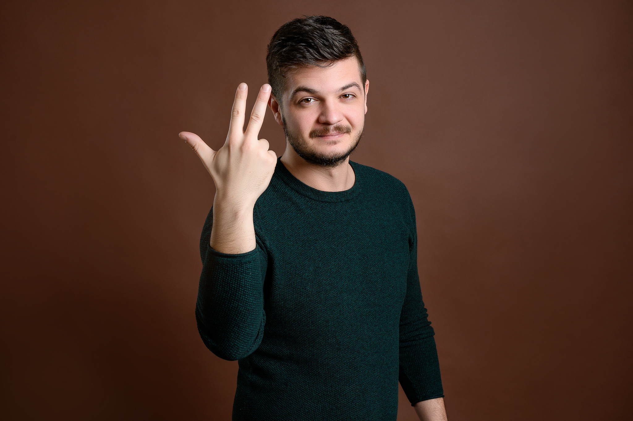 man with brown hair showing number three