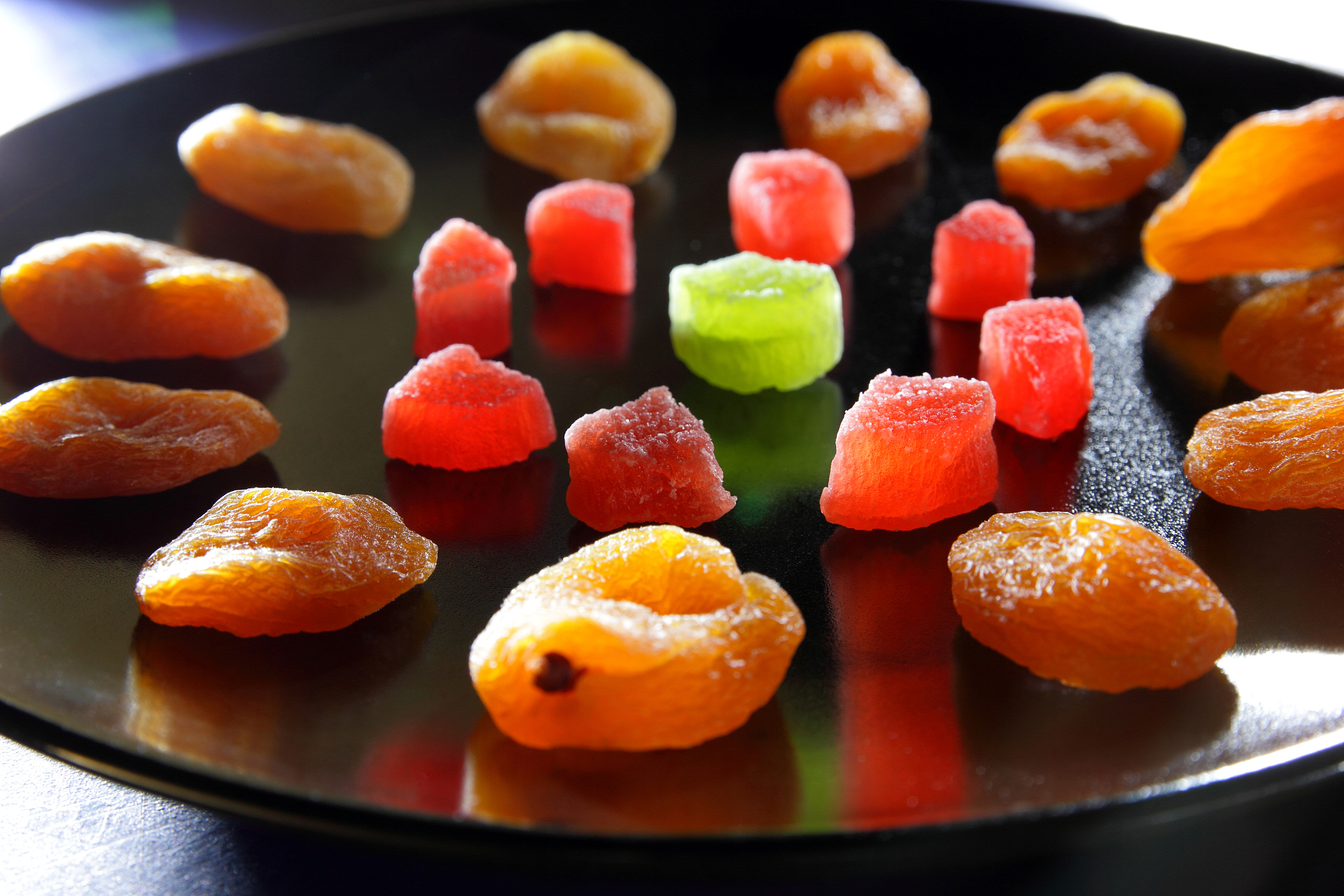 dried apricots, candied fruits in sugar on a black plate on a da