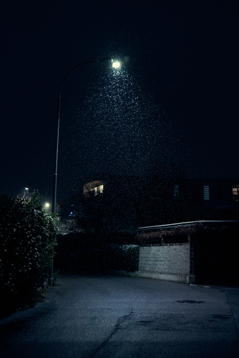 夜间,雨滴落在安静的城市区域的街灯下,湿漉漉的街道