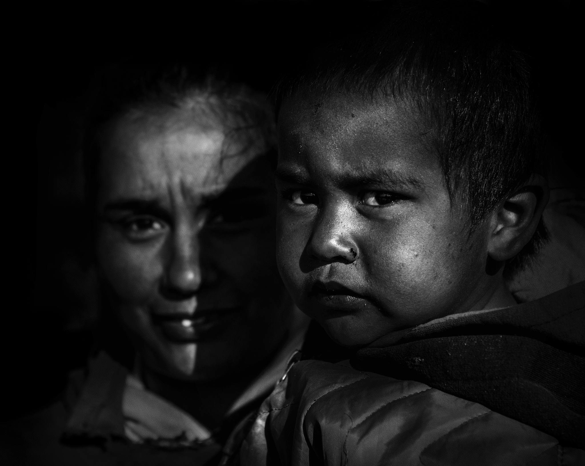 portrait of mother and son against black background
