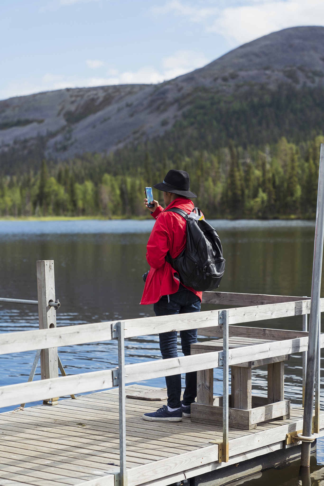 finland, lapland, man taking cell phone picture at the lakeside