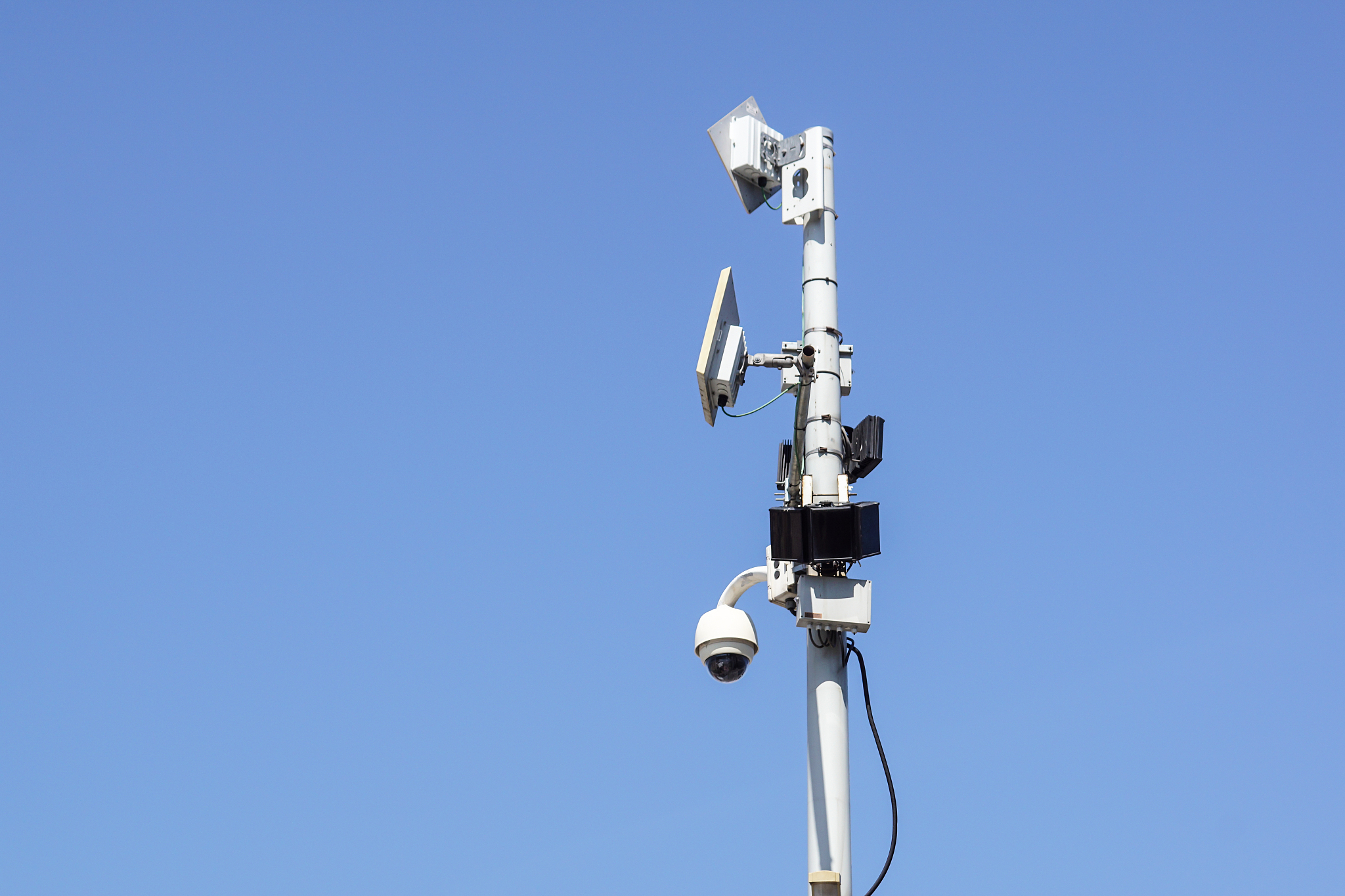 high tech overhead security camera with a blue sky