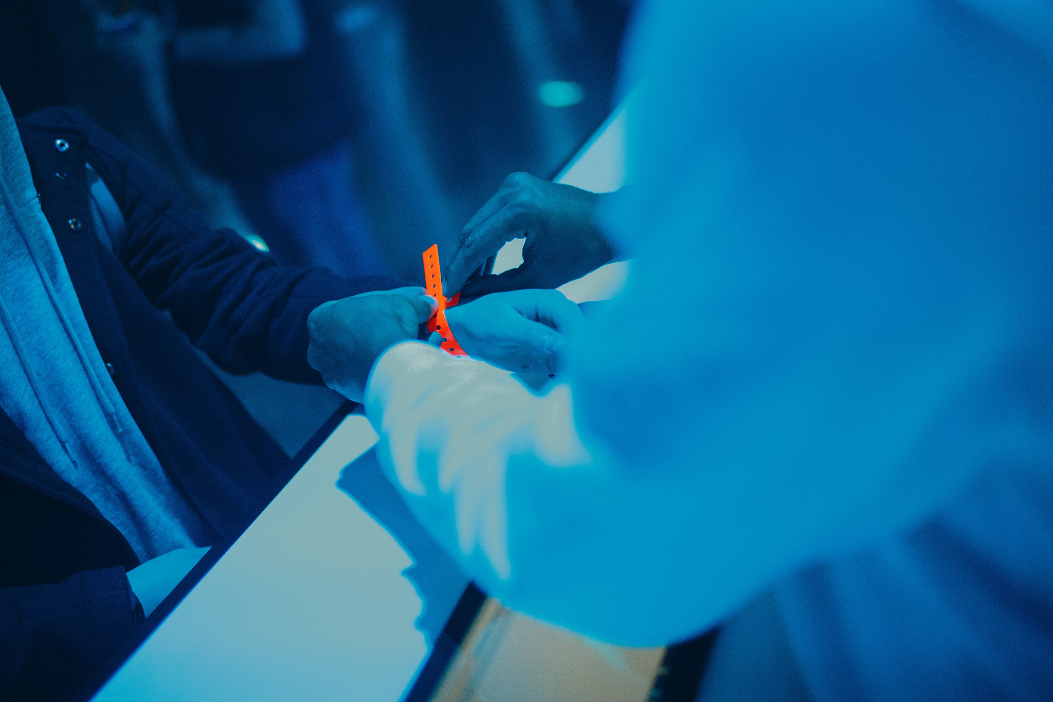 young man put on an orange bracelet in a nightclub