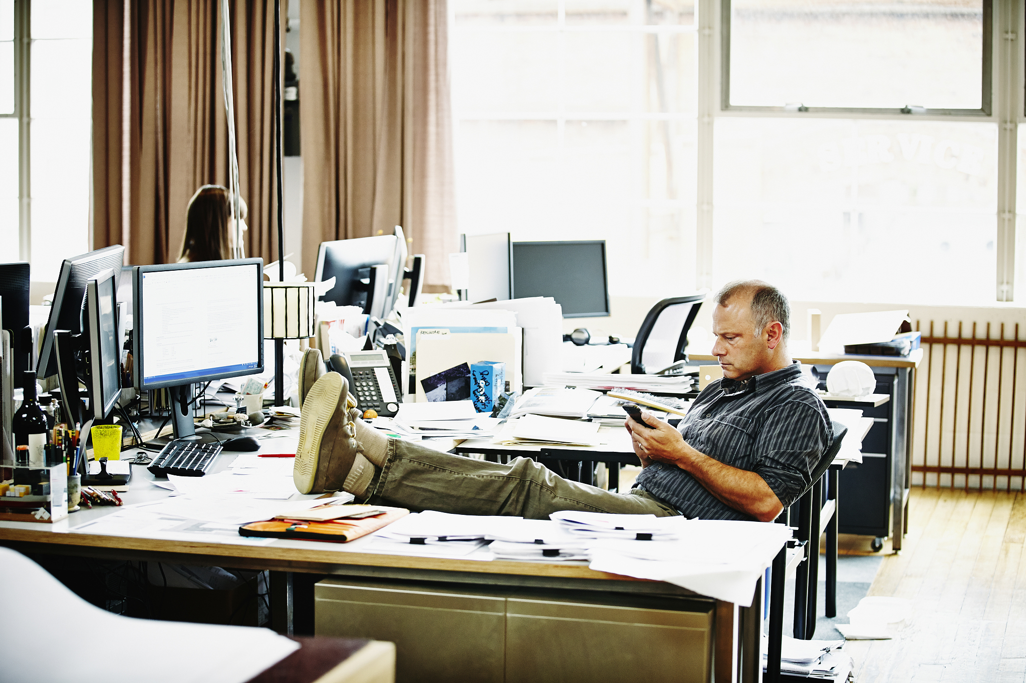 mature architect sitting looking at smartphone