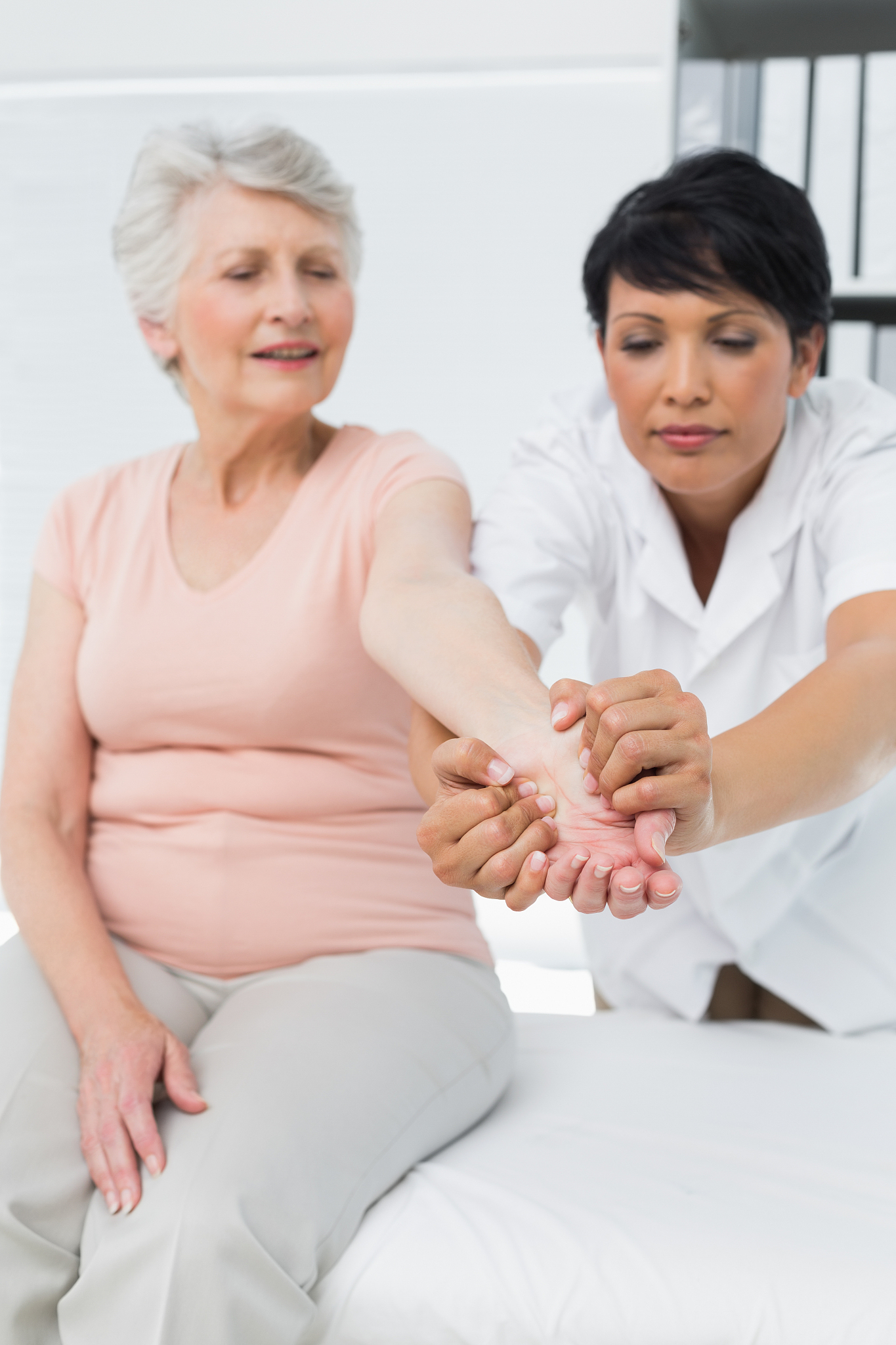 female physiotherapist examining a senior patients hand