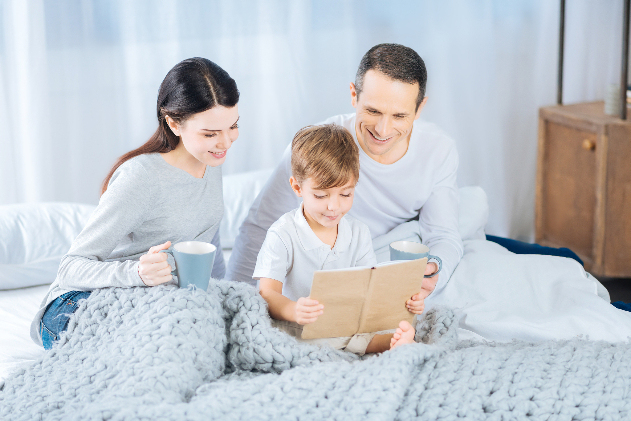 happy parents listening to their son read a book