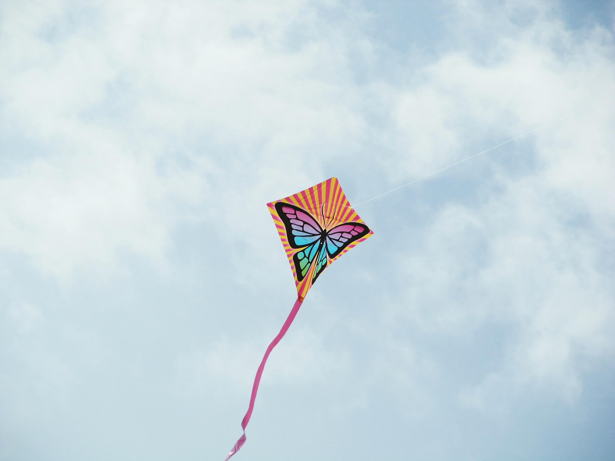 low angle view of kite flying against cloudy sky