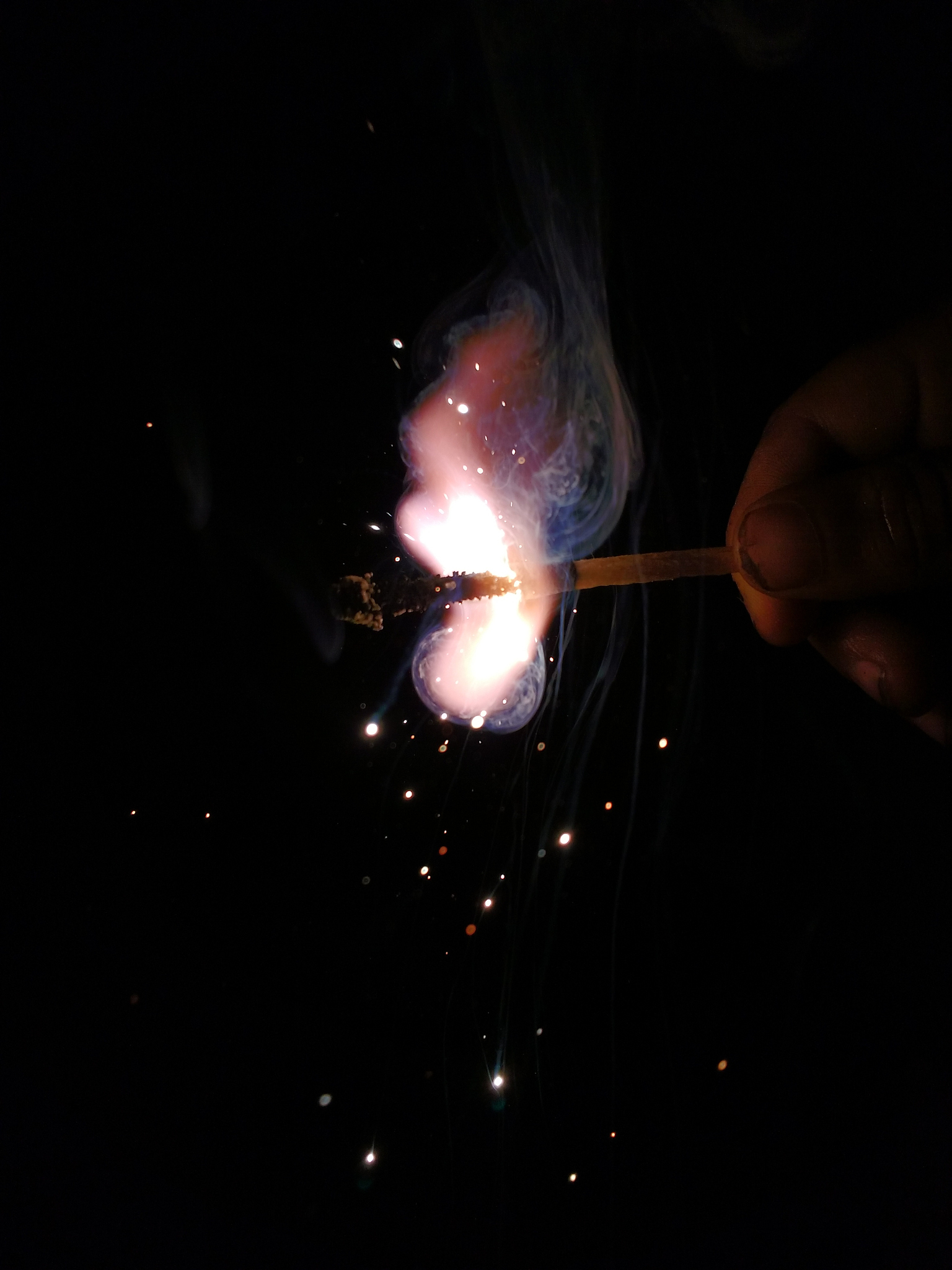 cropped hand of child holding illuminated matchstick at night