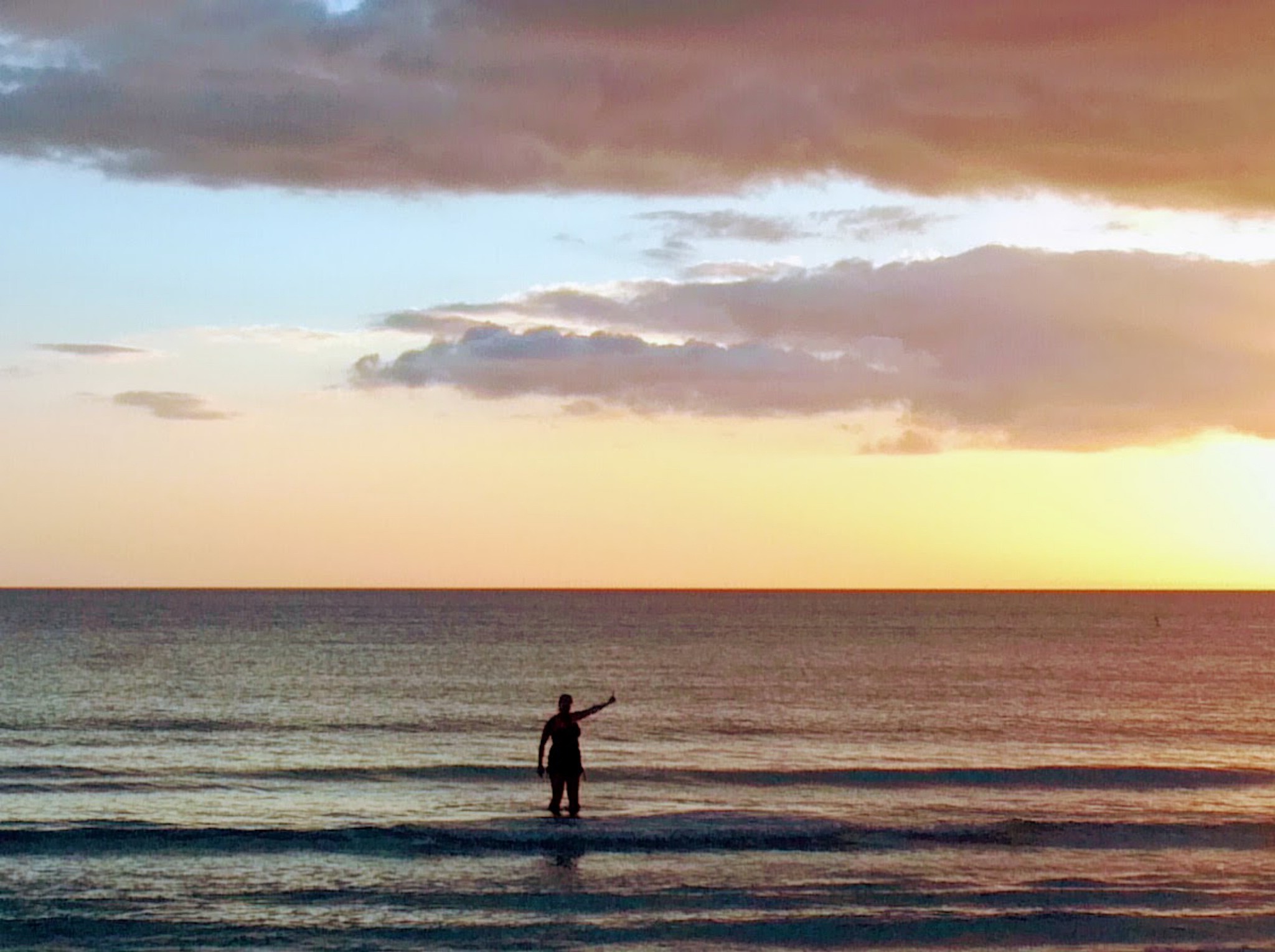 silhouette person standing in sea against sky during sunset