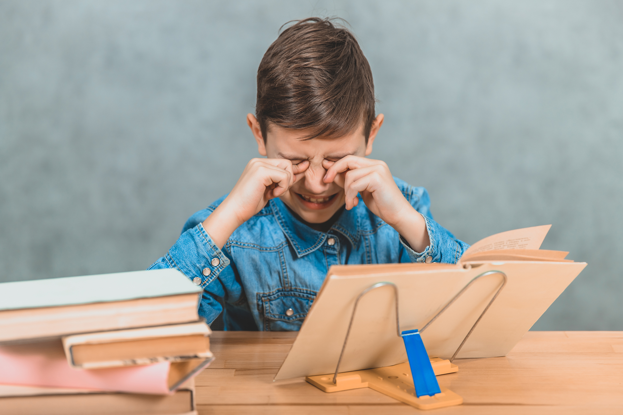 tired schoolkid is crying, rubbing his eyes, because he doesn' t