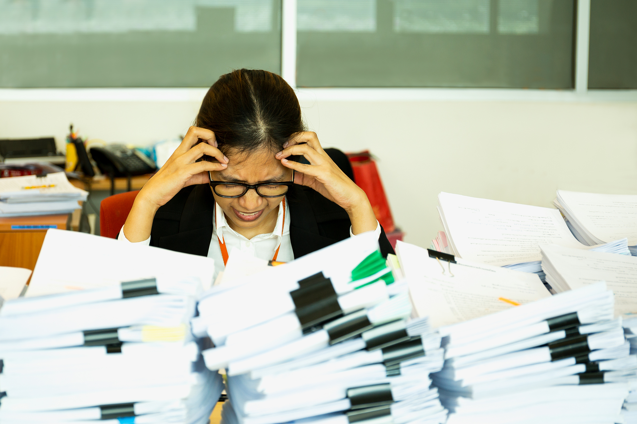office woman worker is distressed with a lot of paperwork on her