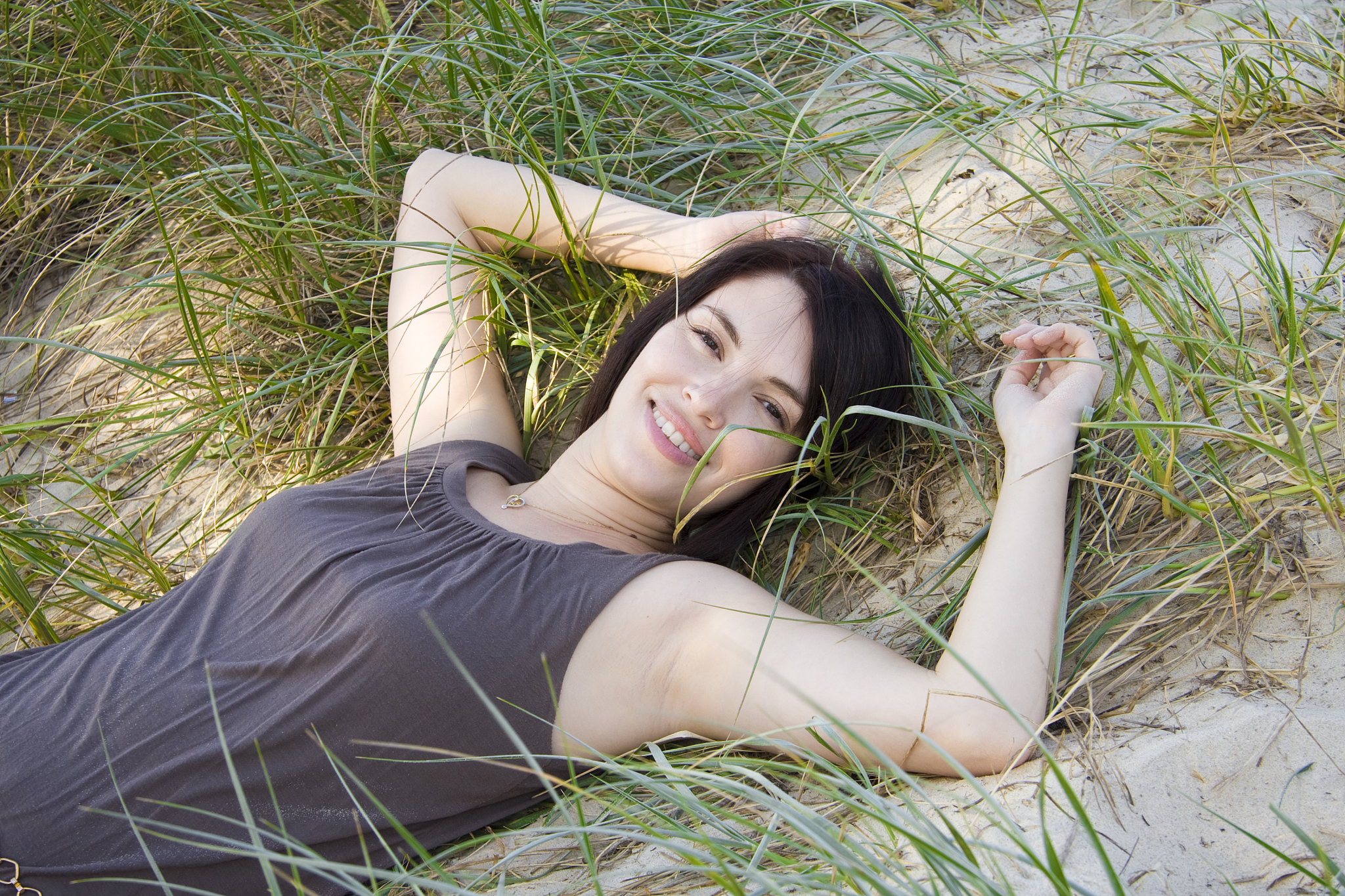 beautiful young woman lying in grassy sand