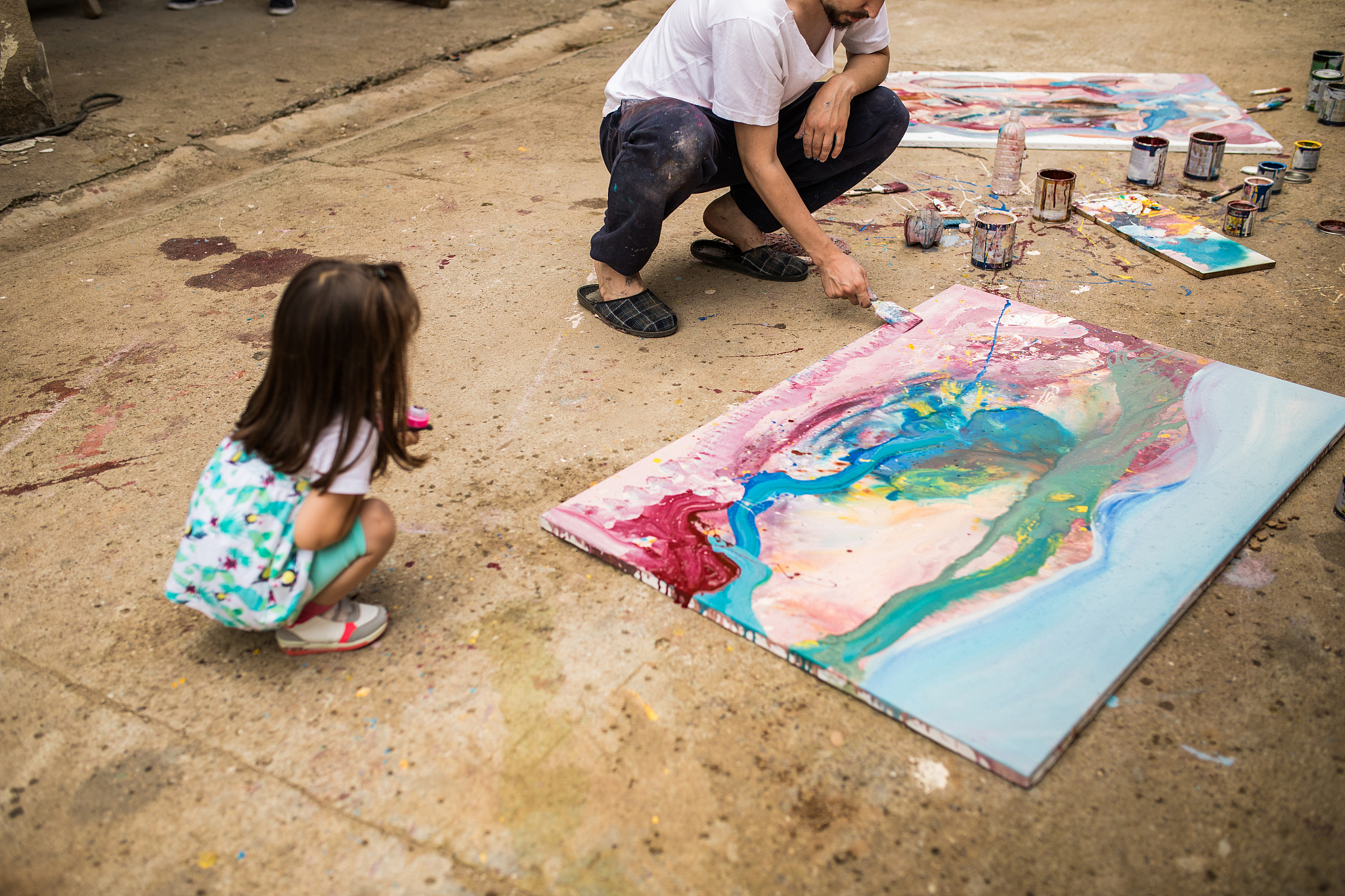 little girl and young man painting together