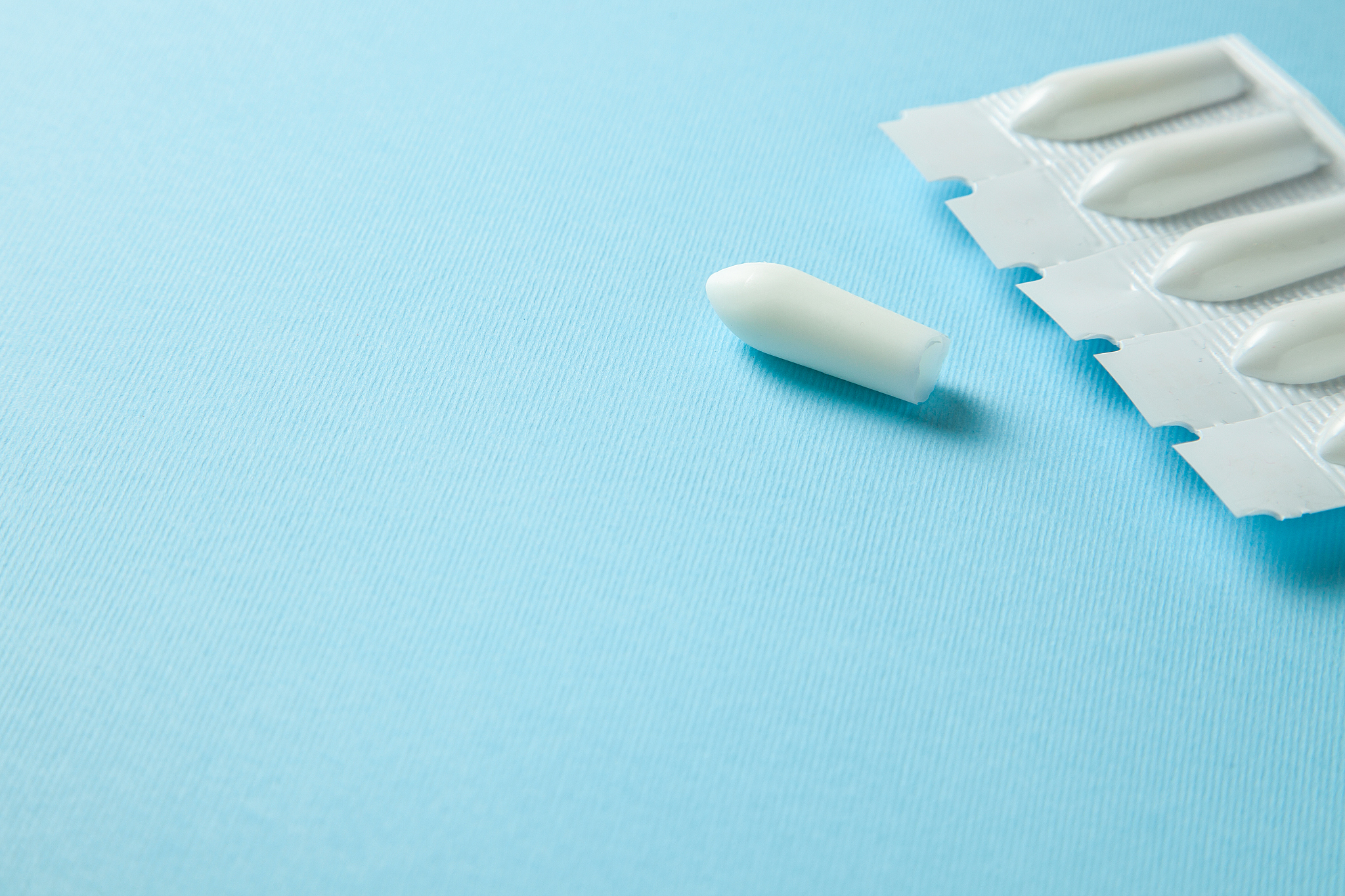 suppository for anal or vaginal use on a blue background. candle