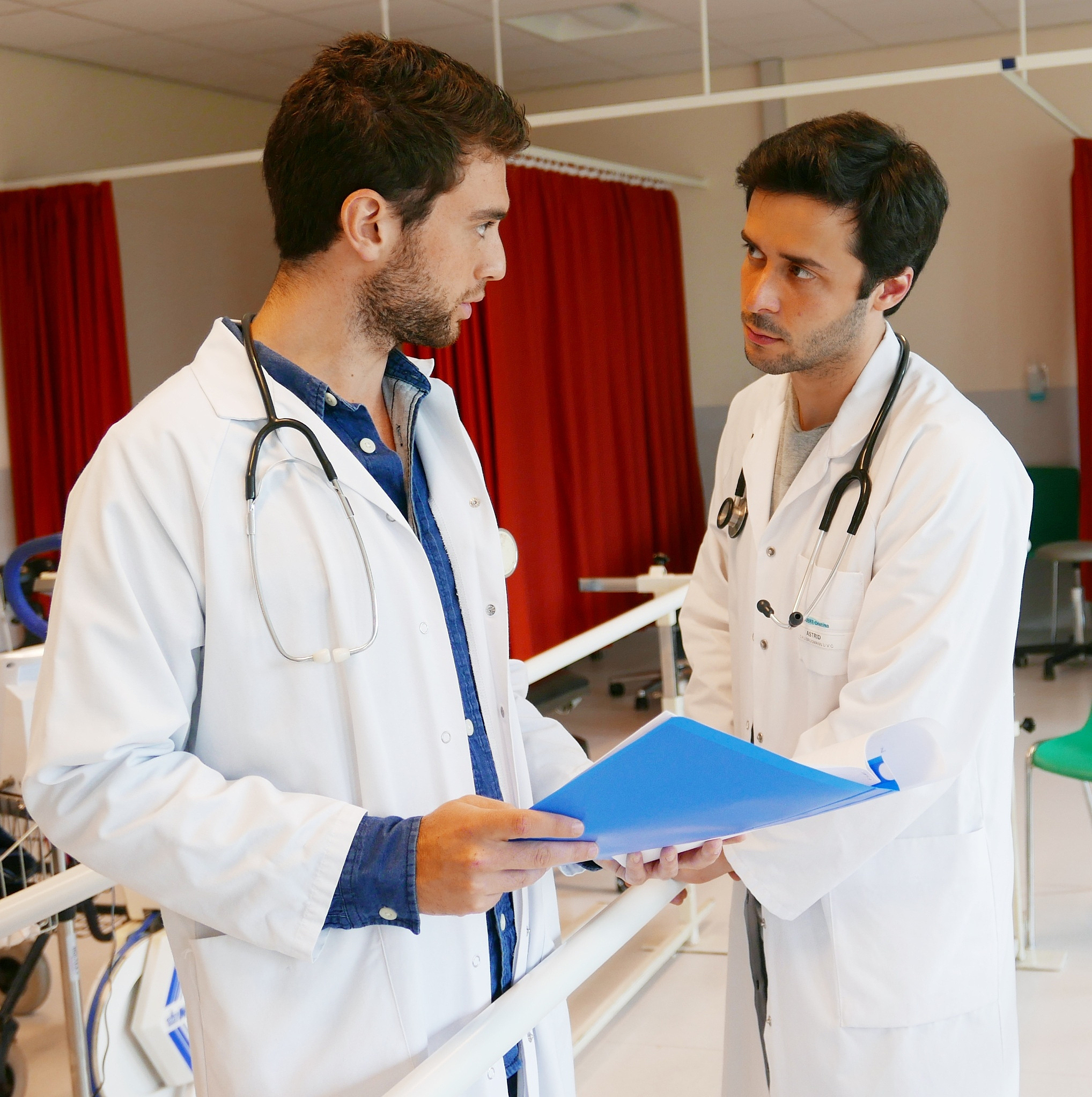 male doctors discussing on document at corridor in hospital