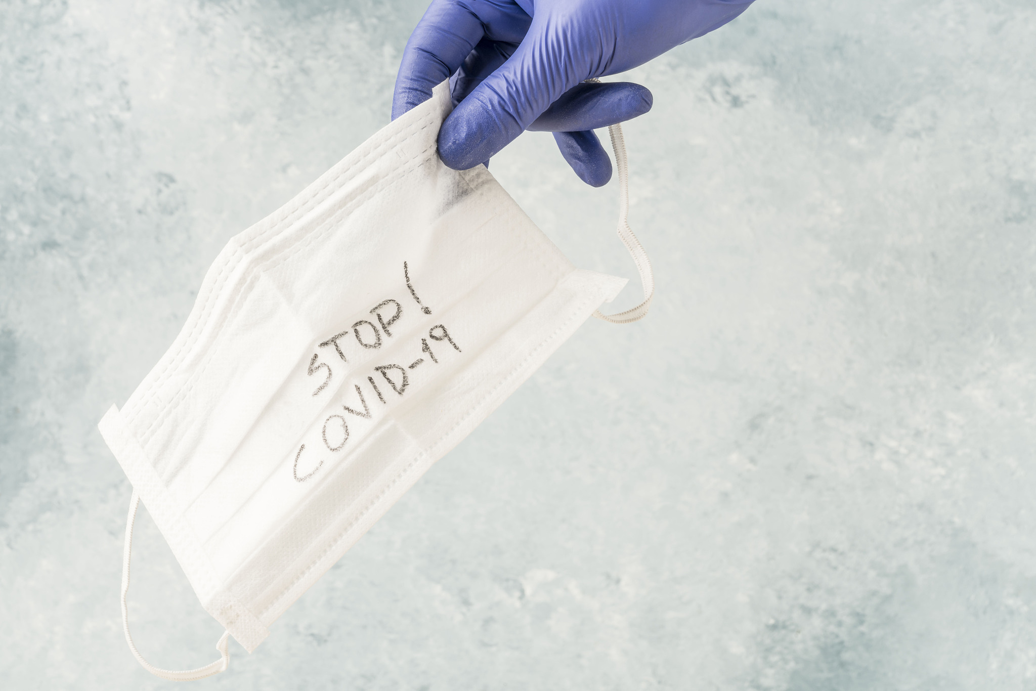 hand in latex glove holding health mask against covid-19