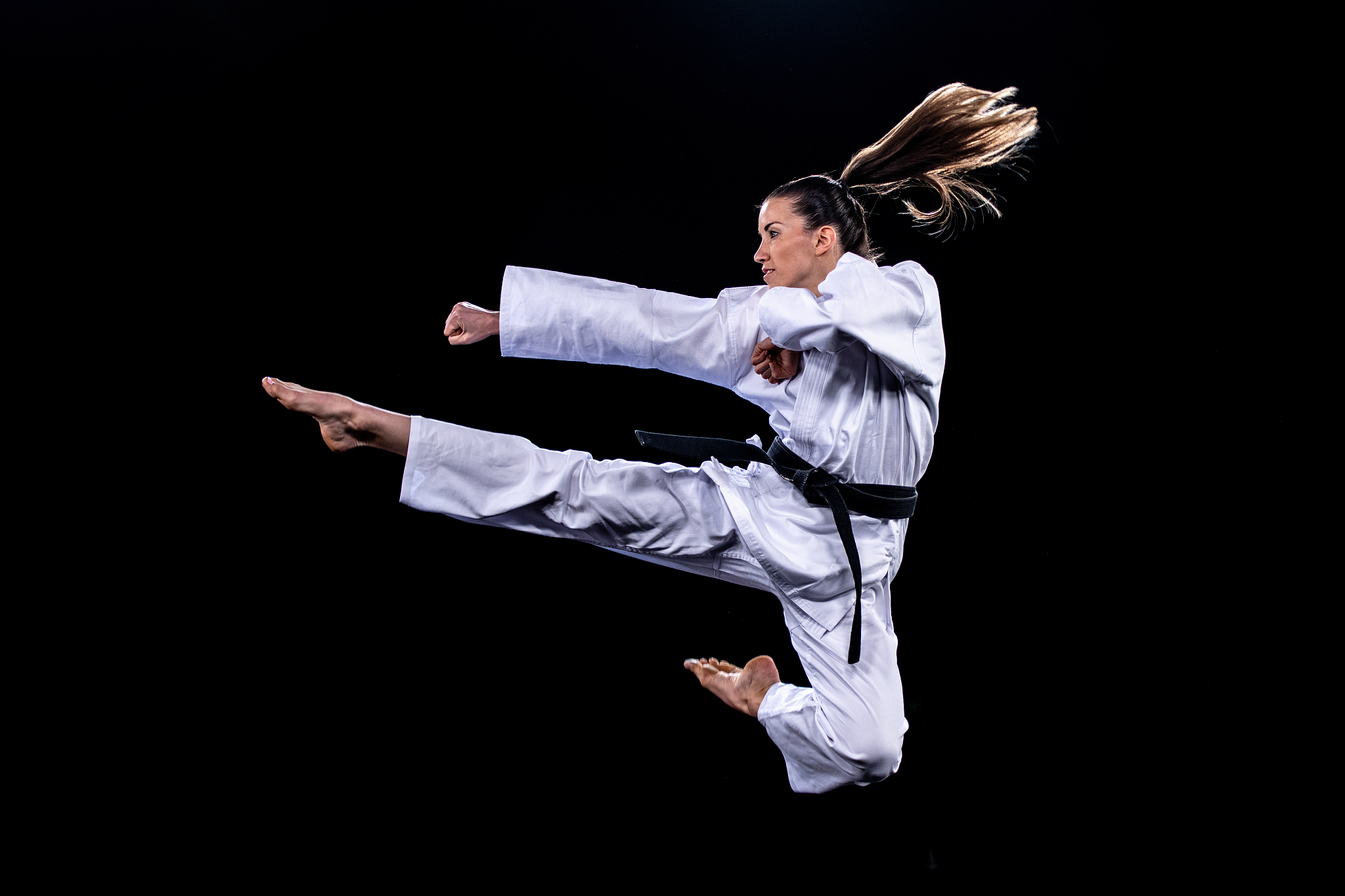 female karate player jumping in air for kick