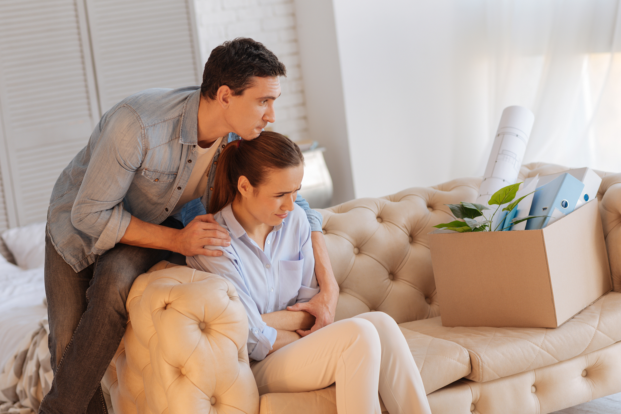 upset young woman almost crying while her calm husband hugging h