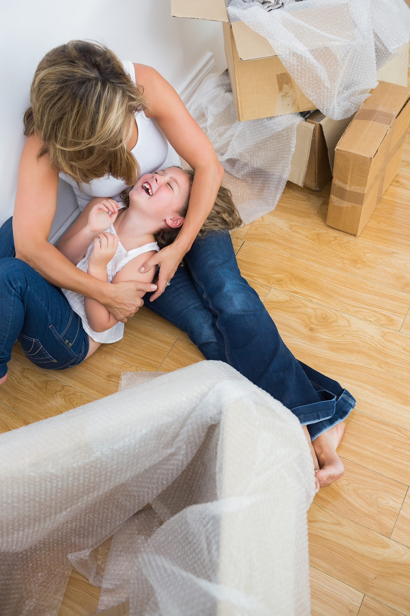 mother tickling her daughter on the floor