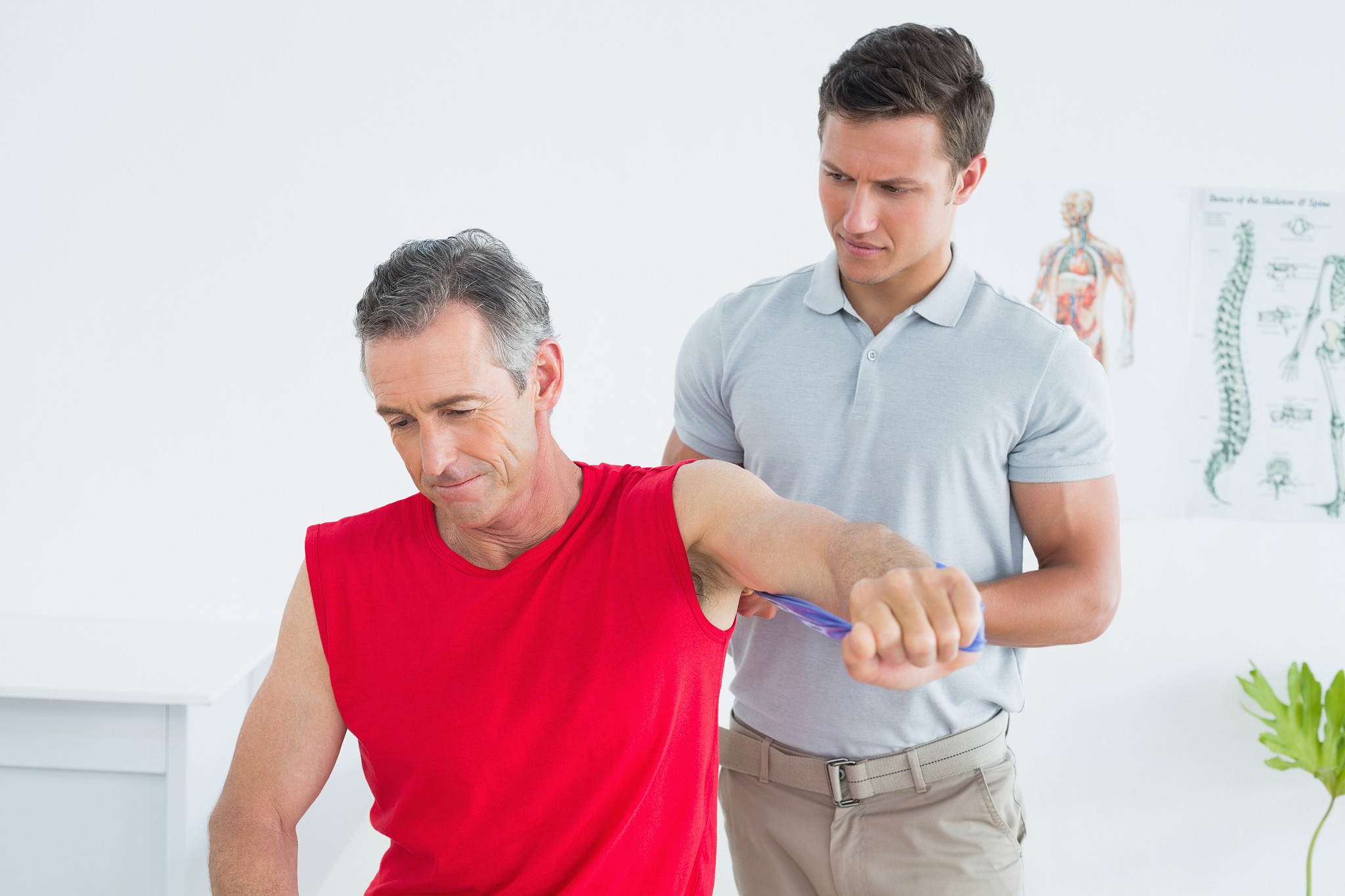 male physiotherapist examining a mature mans arm
