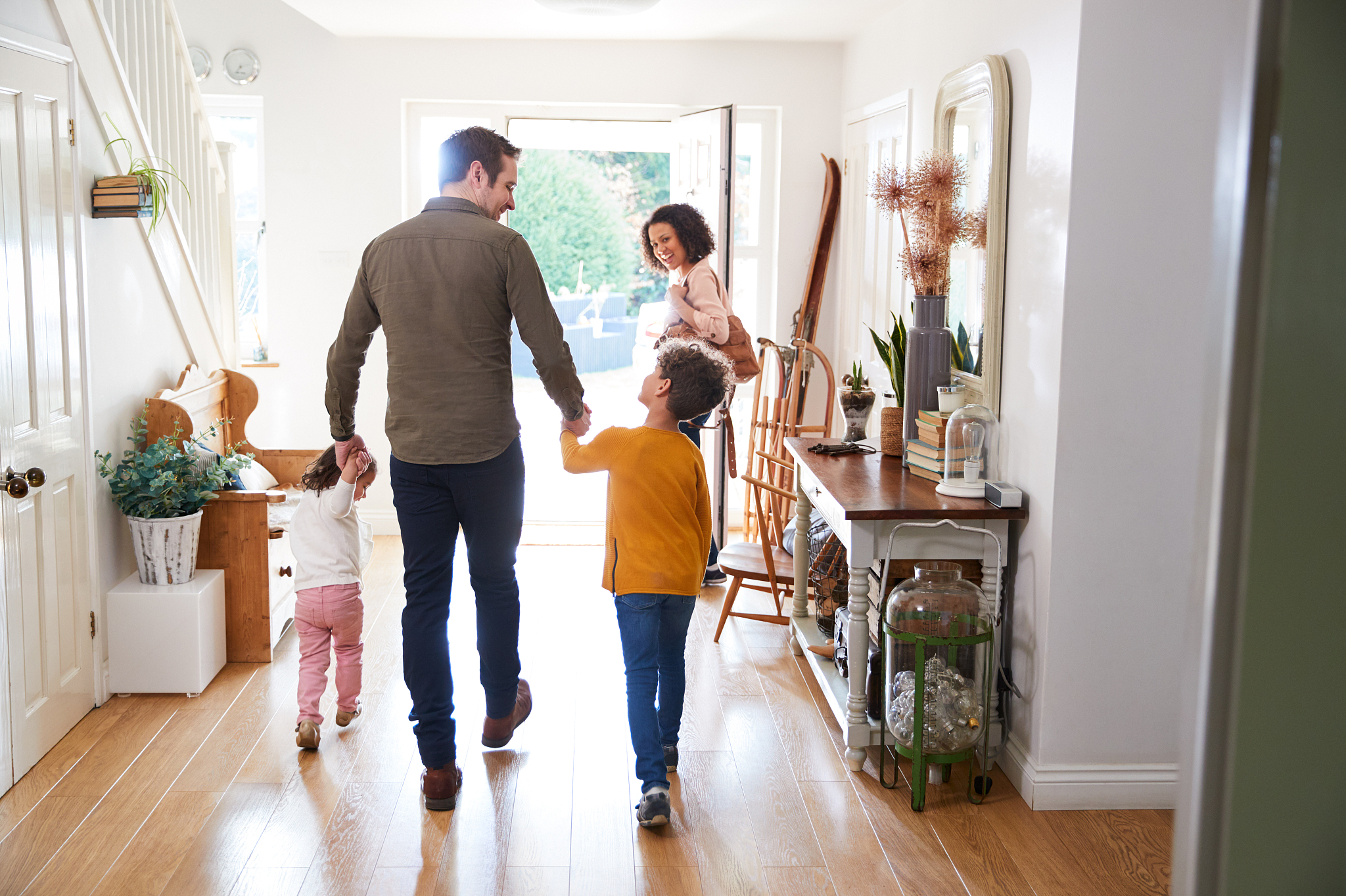 rear view of family leaving home on trip out with excited childr