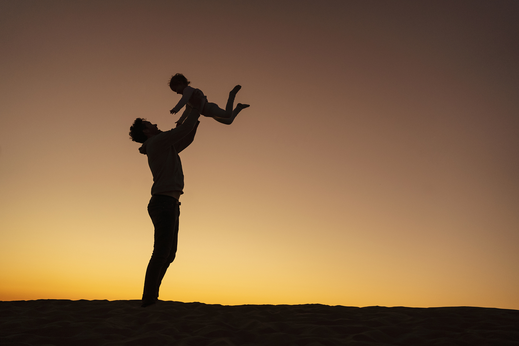 father playing with daughter on sand dune at sunset, gran canari