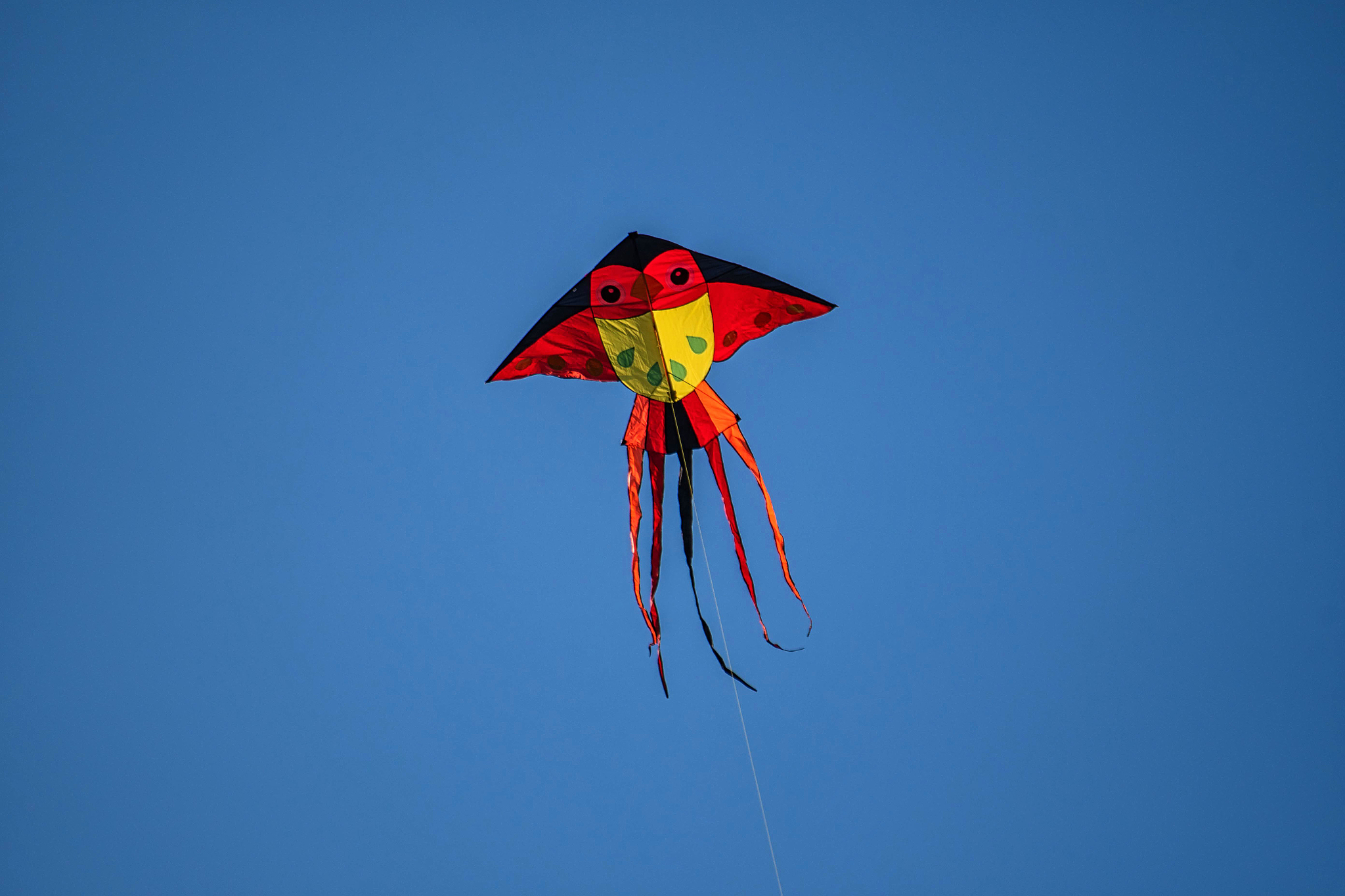 low angle view of kite flying against clear blue sky