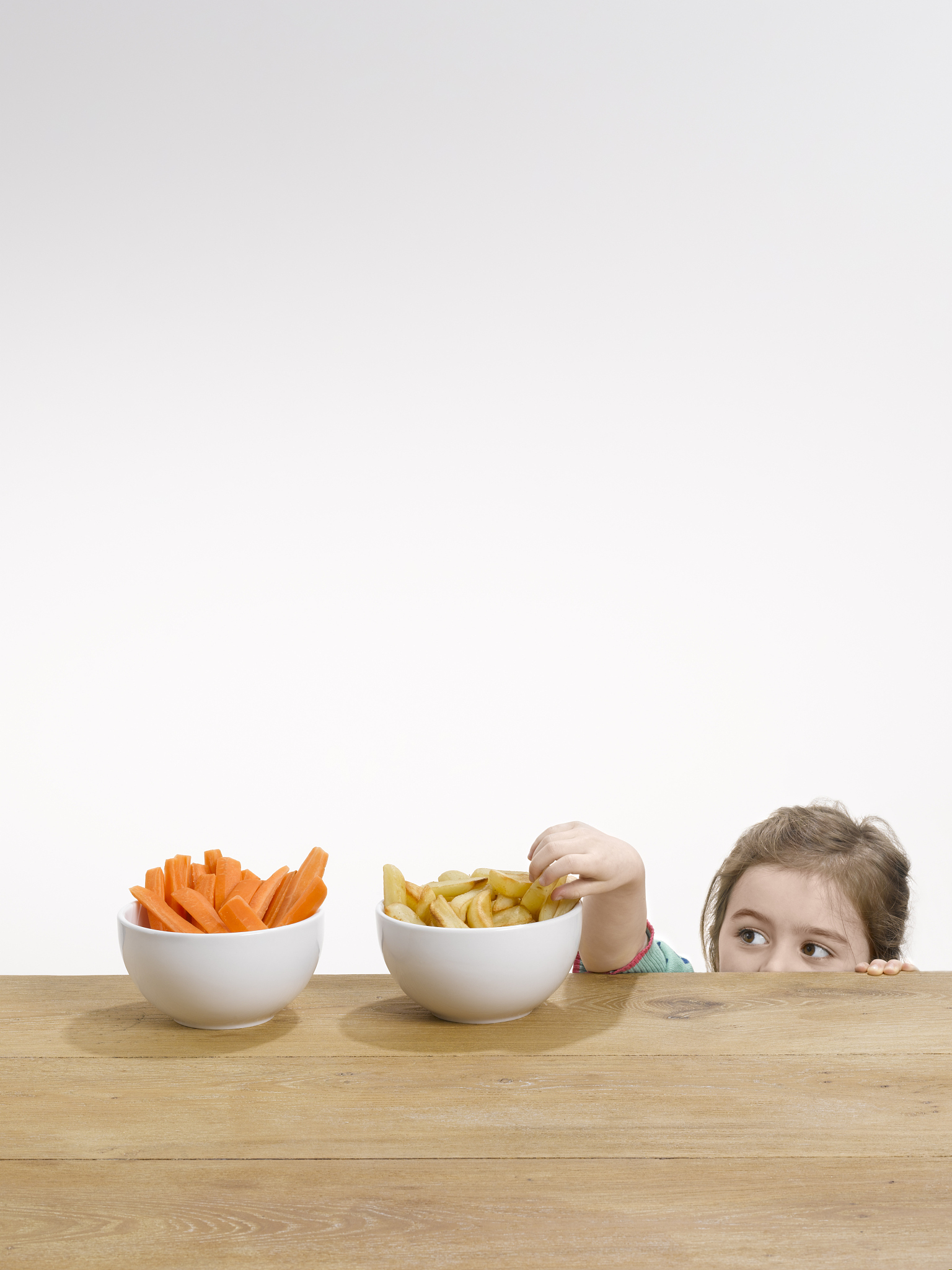 small girl pinching chips from a bowl