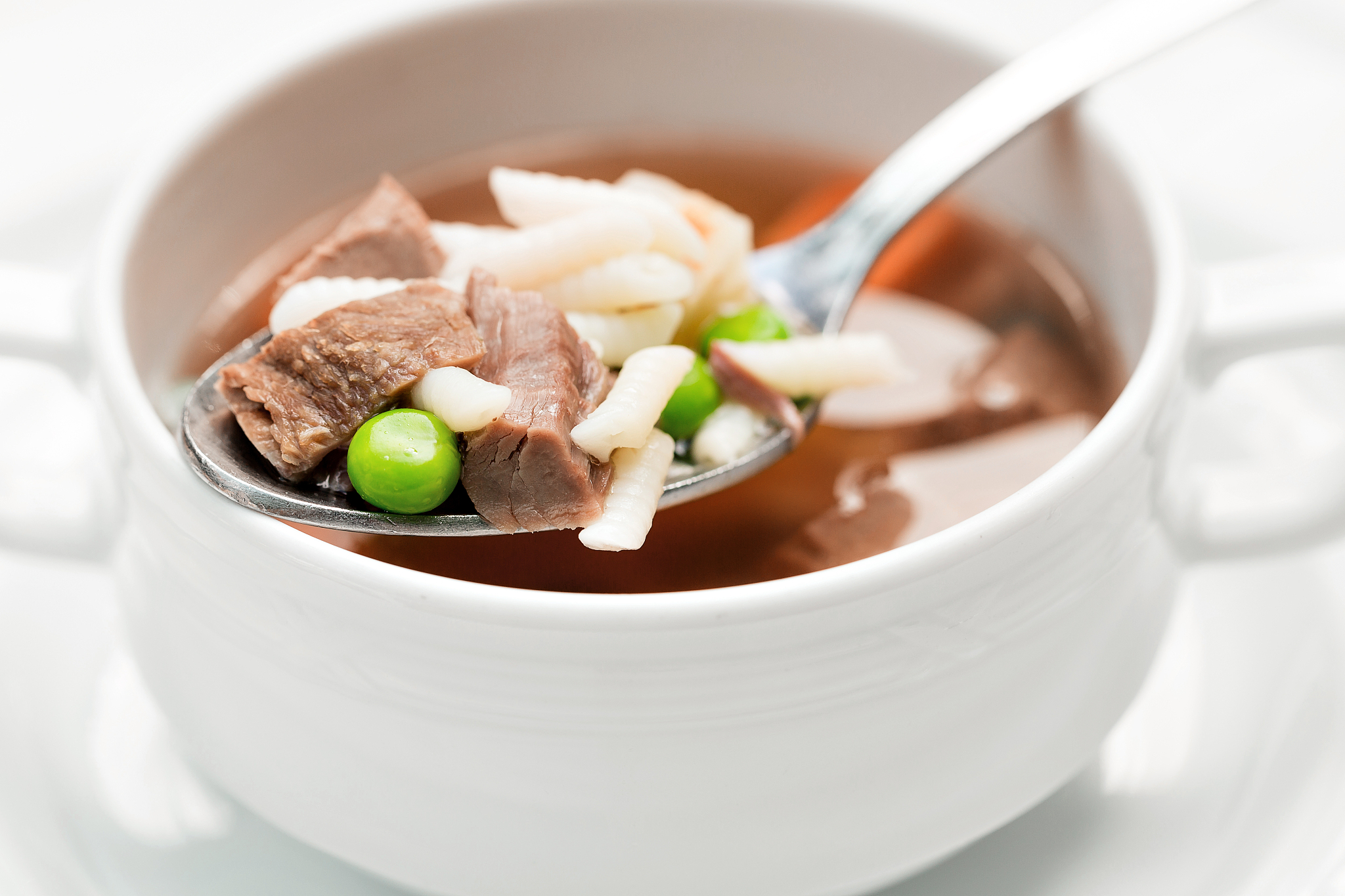 a bowl of delicious beef and barley soup with carrots, tomato, p