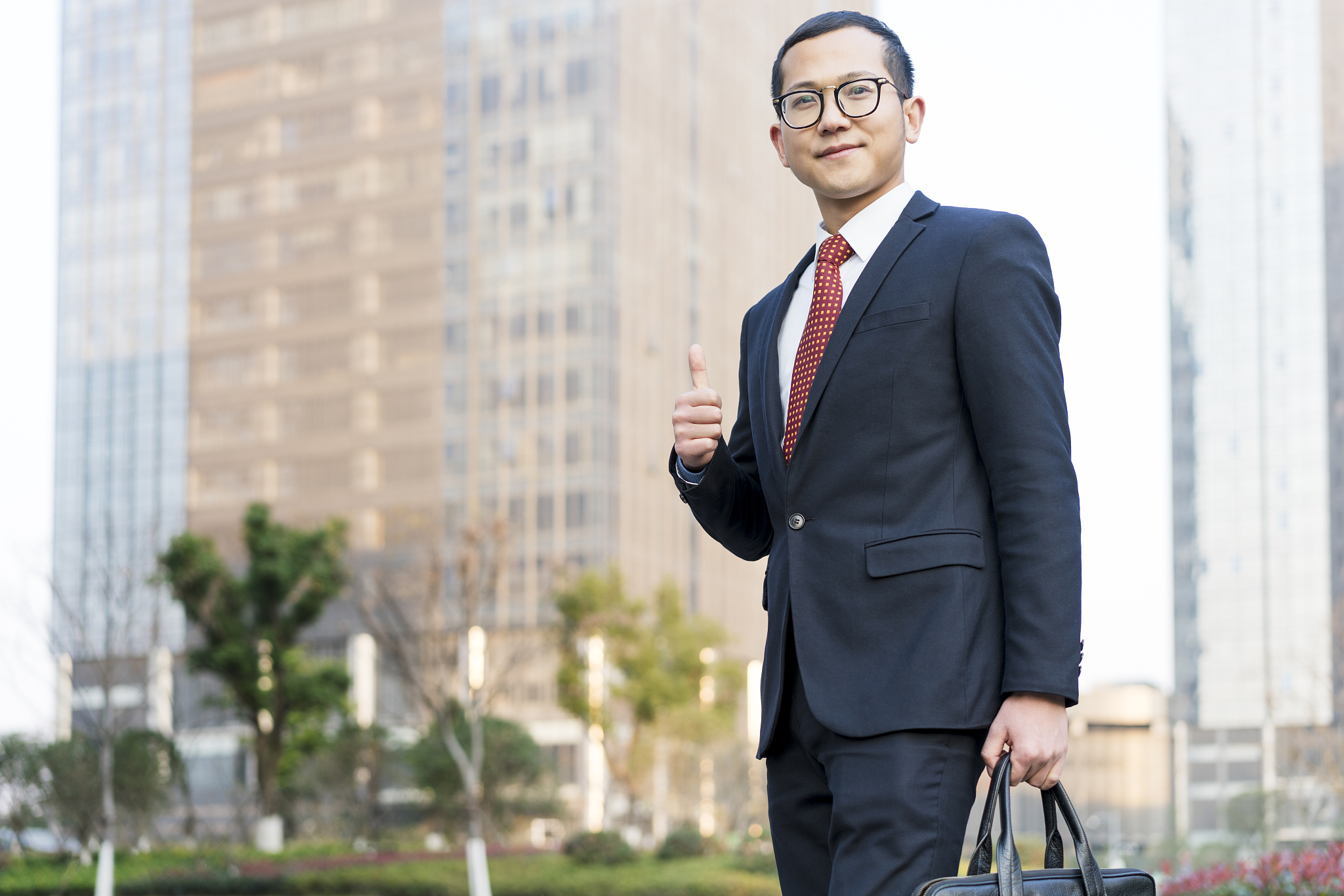 young businessman thumbs up outside office building