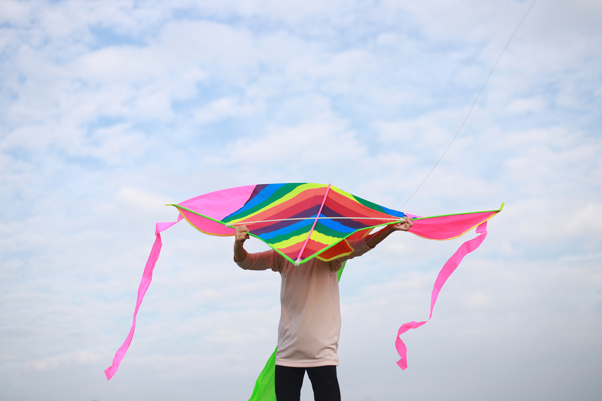 asian girls playing and flying kite in a meadow.