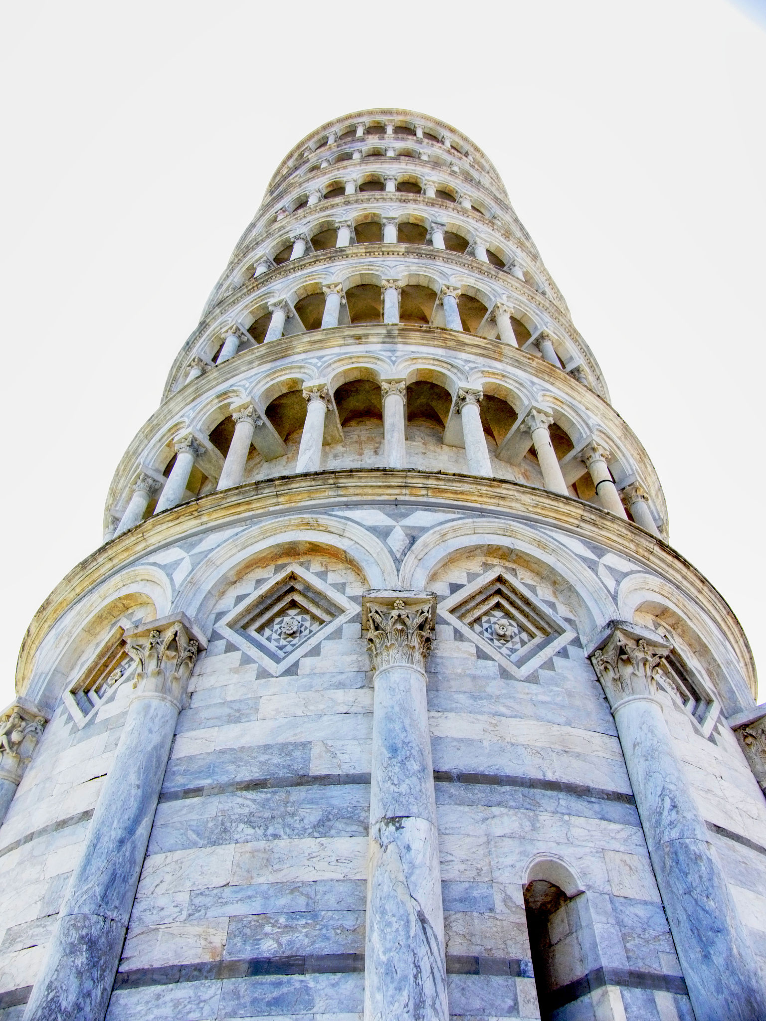 将以下文字变得通顺 但是不要删减内容：并不在于比萨斜塔不仅仅在于比萨斜塔正一点儿它才是好看的而在于我觉得这里面可能一个很重要的方式就是肖尔用某种技术手段去解决照片中的平面性问题。我们想象这个如果酒店是正的车也是斜的那那个塔就会更斜可能会有种失衡的感觉。所以它微微向左旋转啊让那个车跟着这个酒店整体上拉开一个横条。我们看整个画面是一个横条的一个结构哈这样来在照片中显得比较正呃就是整整体的效果显得比较正