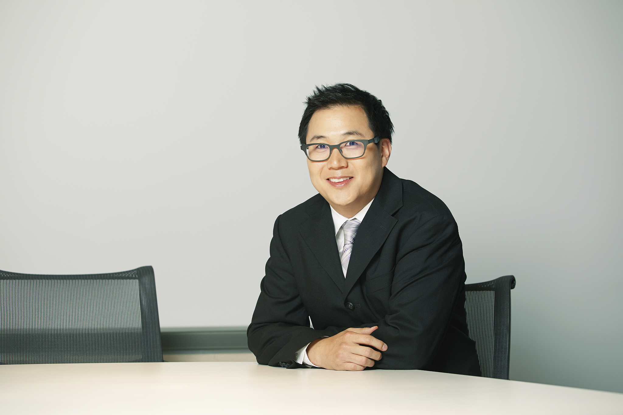 businessman sitting at desk, looking at camera