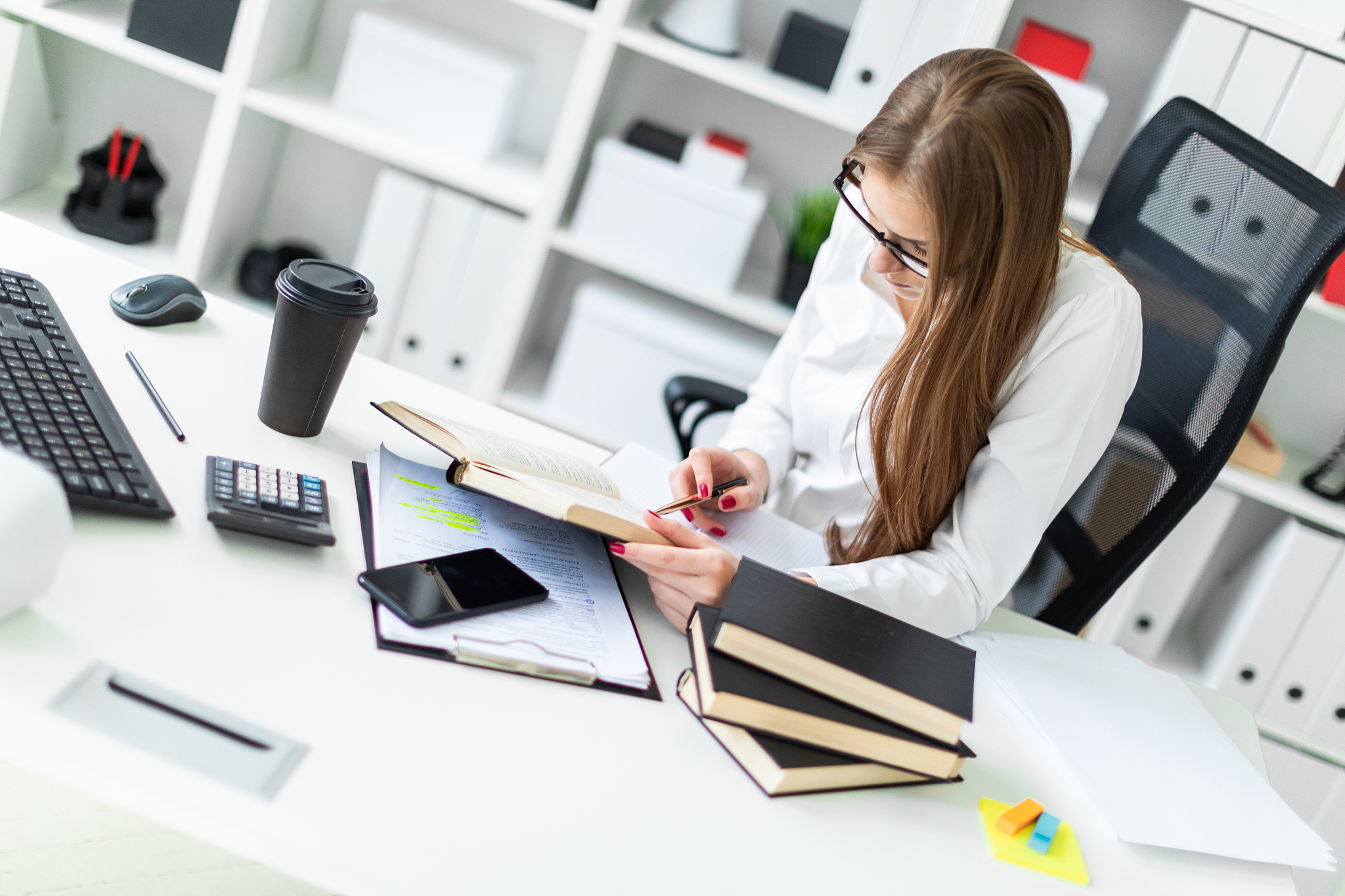 a young girl working in the office with books and documents.