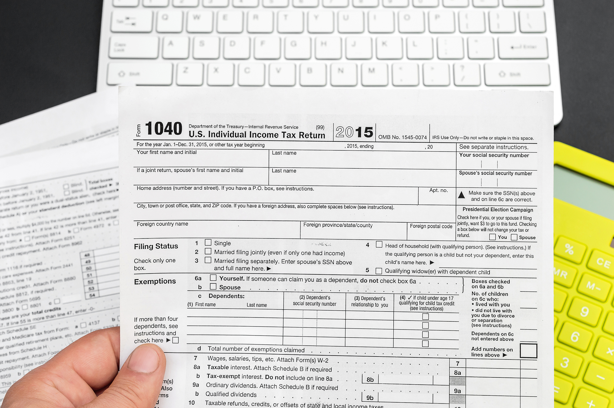 man's hand holding tax form over office workplace.