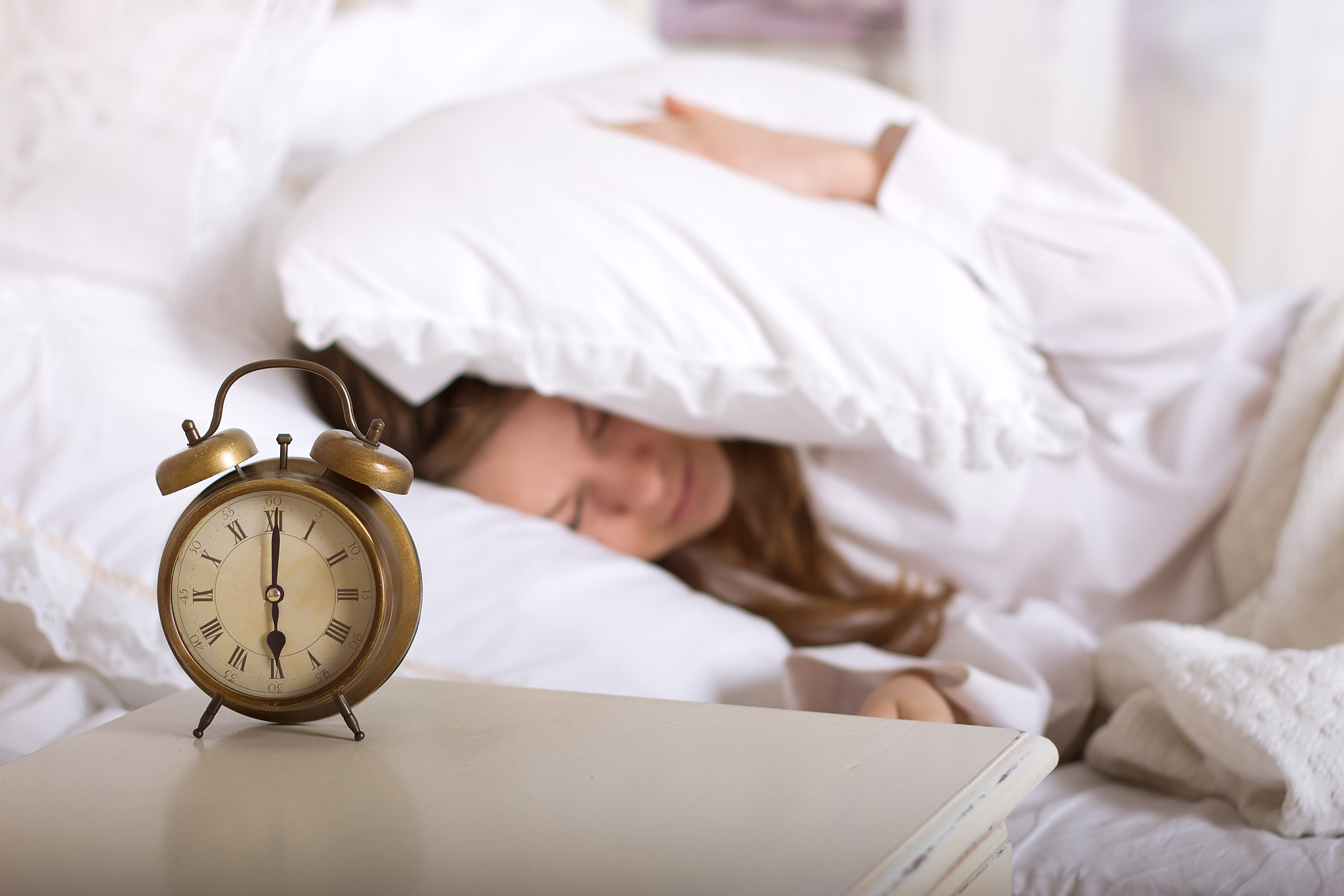 alarm clock on table and woman sleeping