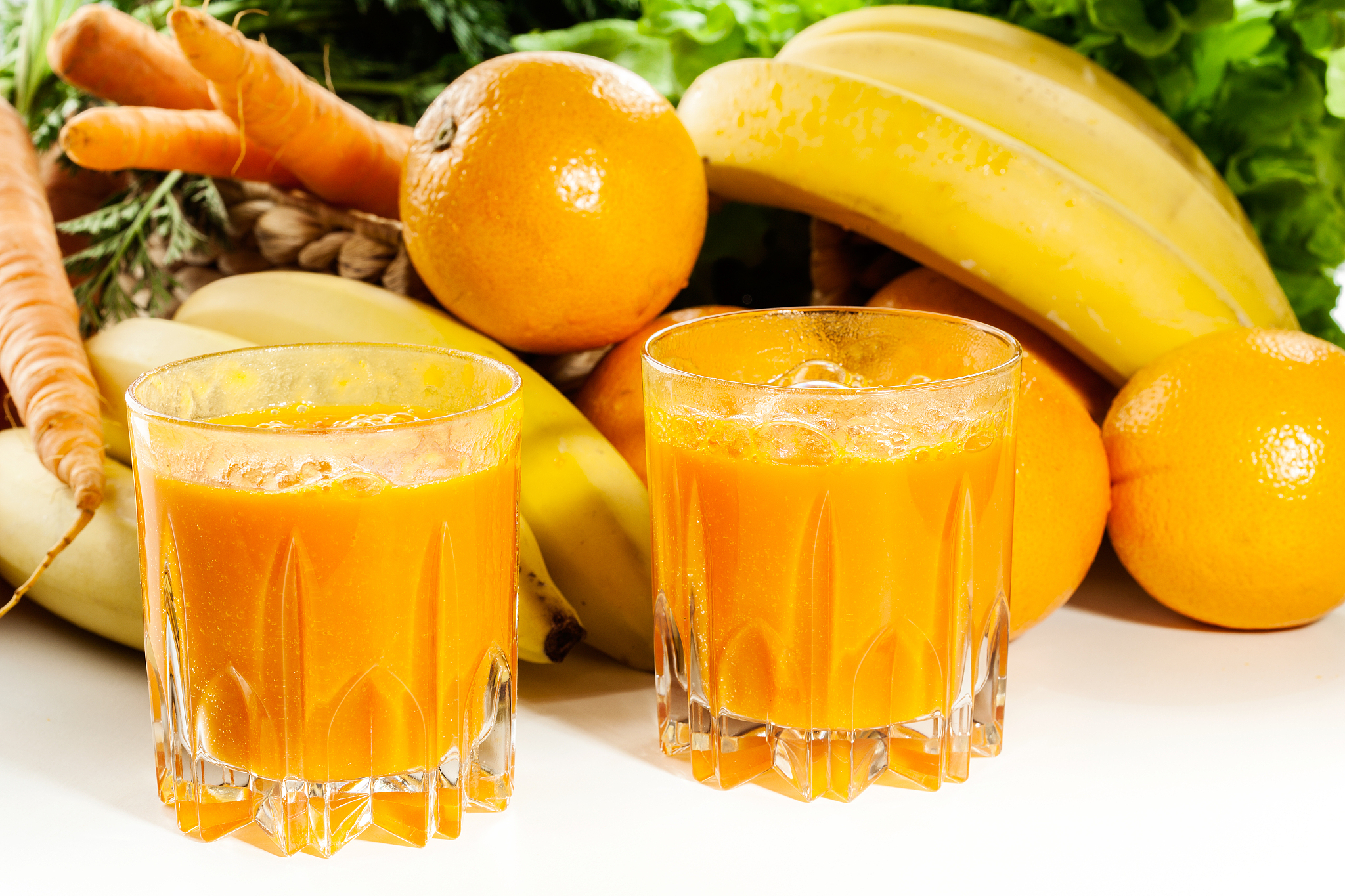 glass of fruit juice with orange, carrots and banana