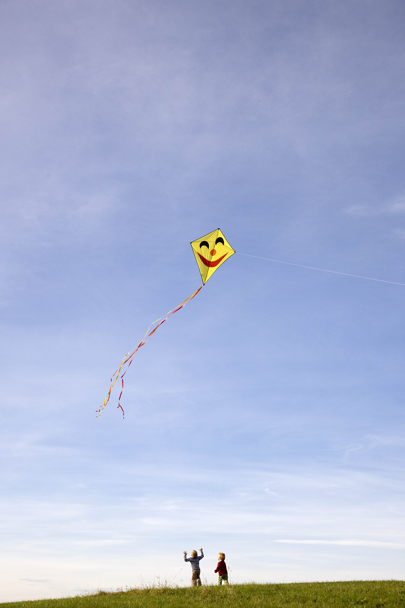 two boys fly a kite