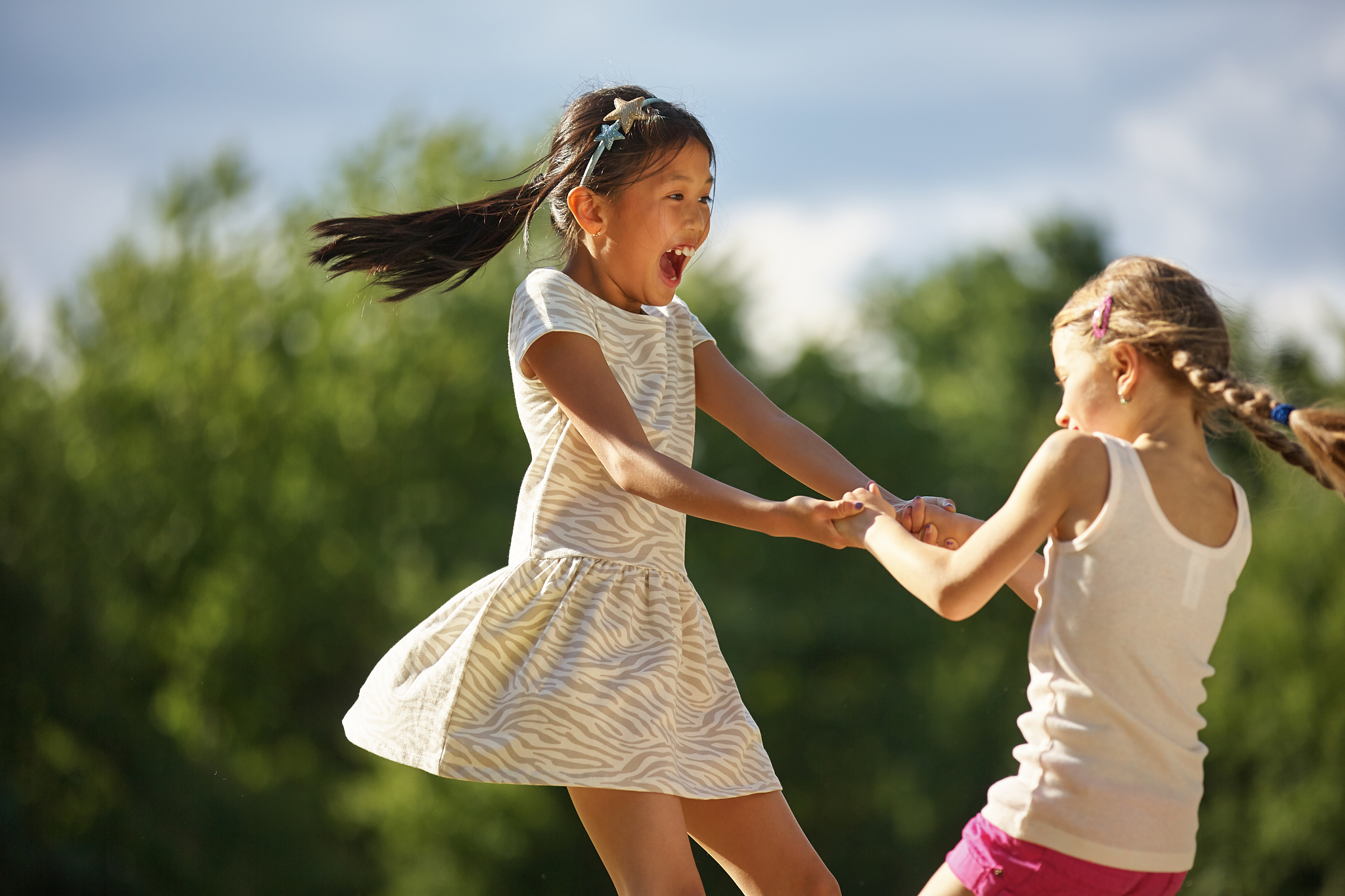 cheerful girl dancing with female friend at park