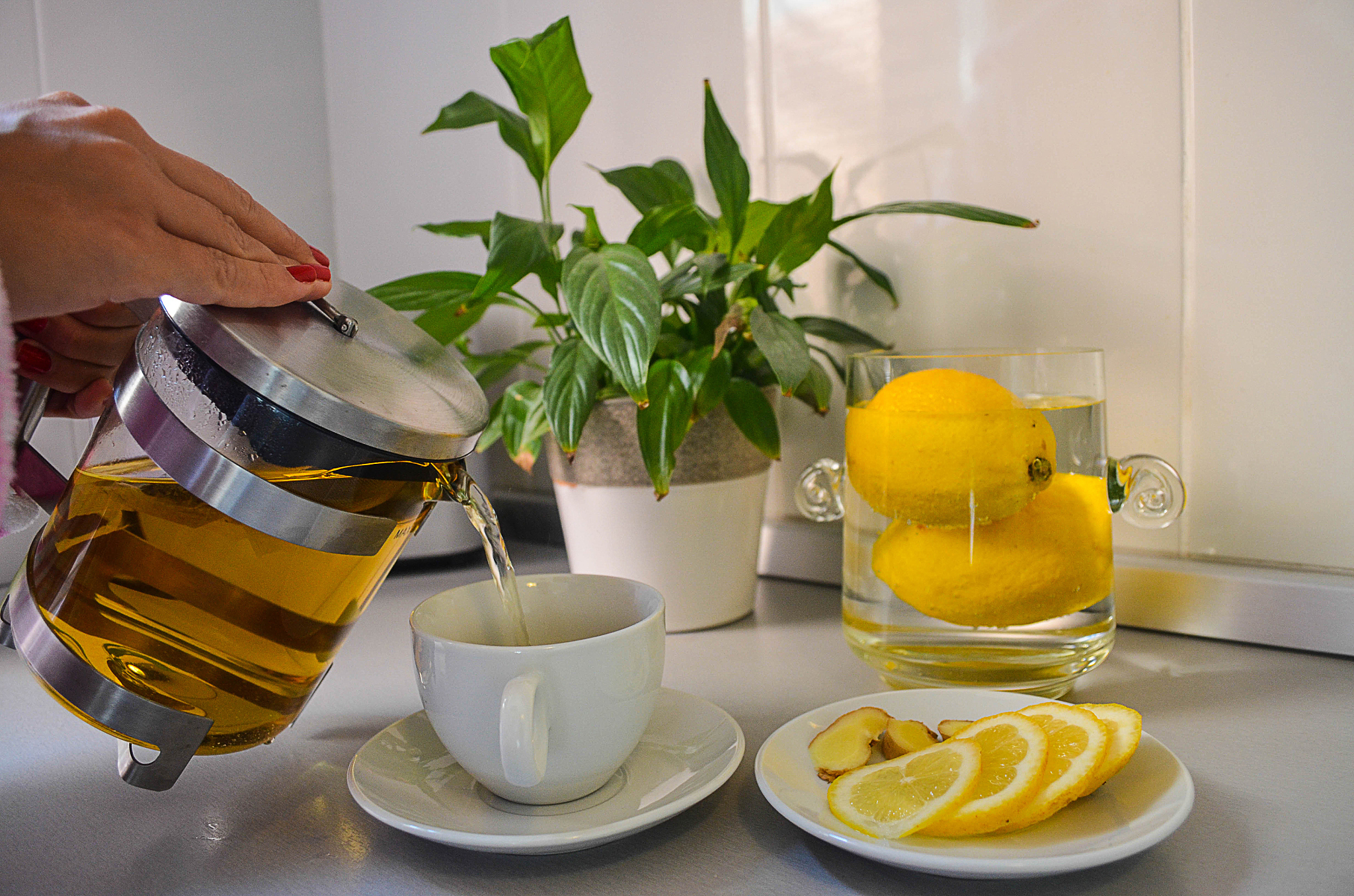 woman is using a teapot to pour a tea in the cup
