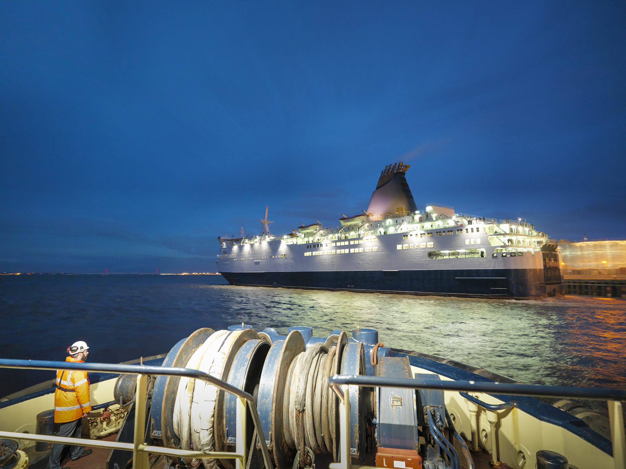 view of passenger ferry out to sea at night, as seen from tug