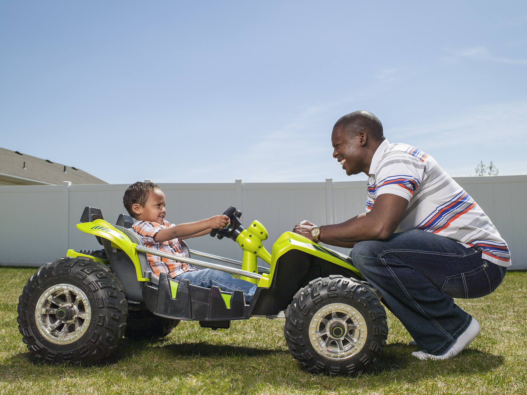 father with son riding in toy dune buggy
