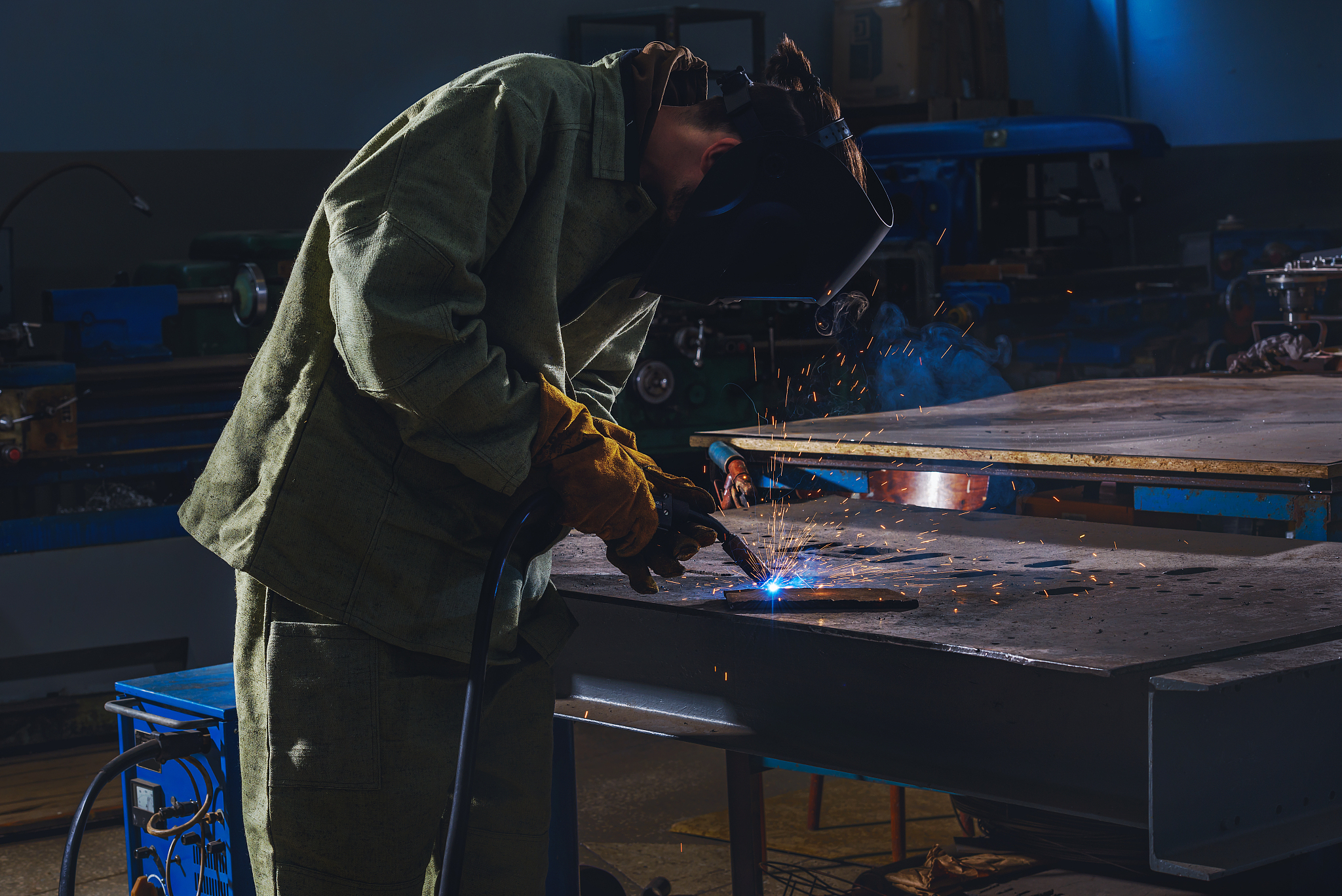 concentrated manufacture worker welding metal with sparks at fac