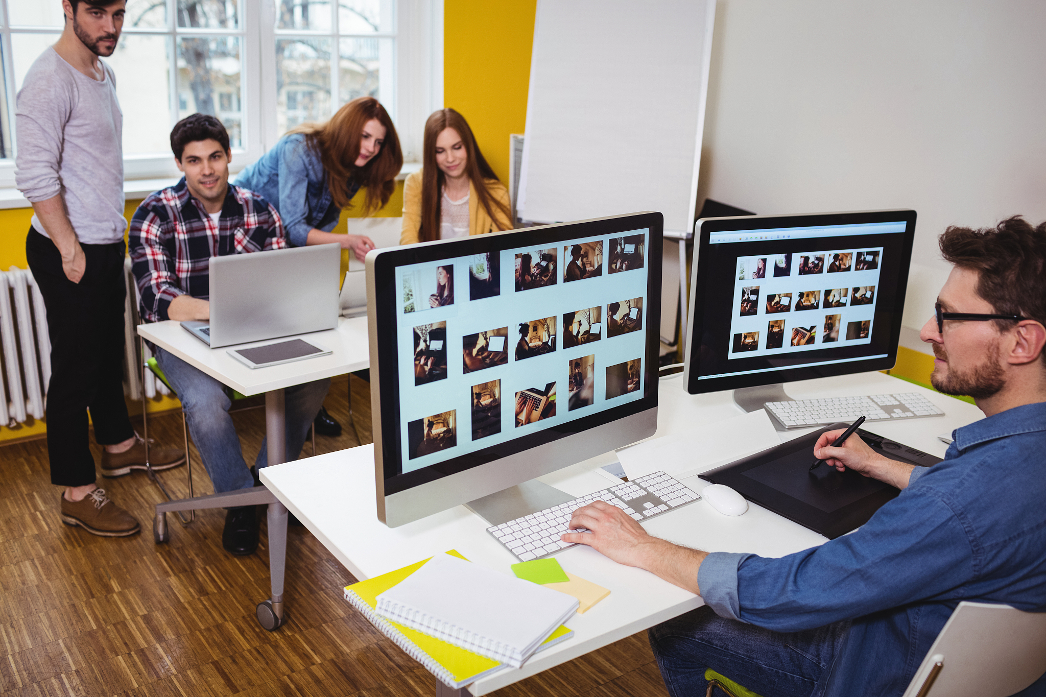 photo editor working on computer against coworkers