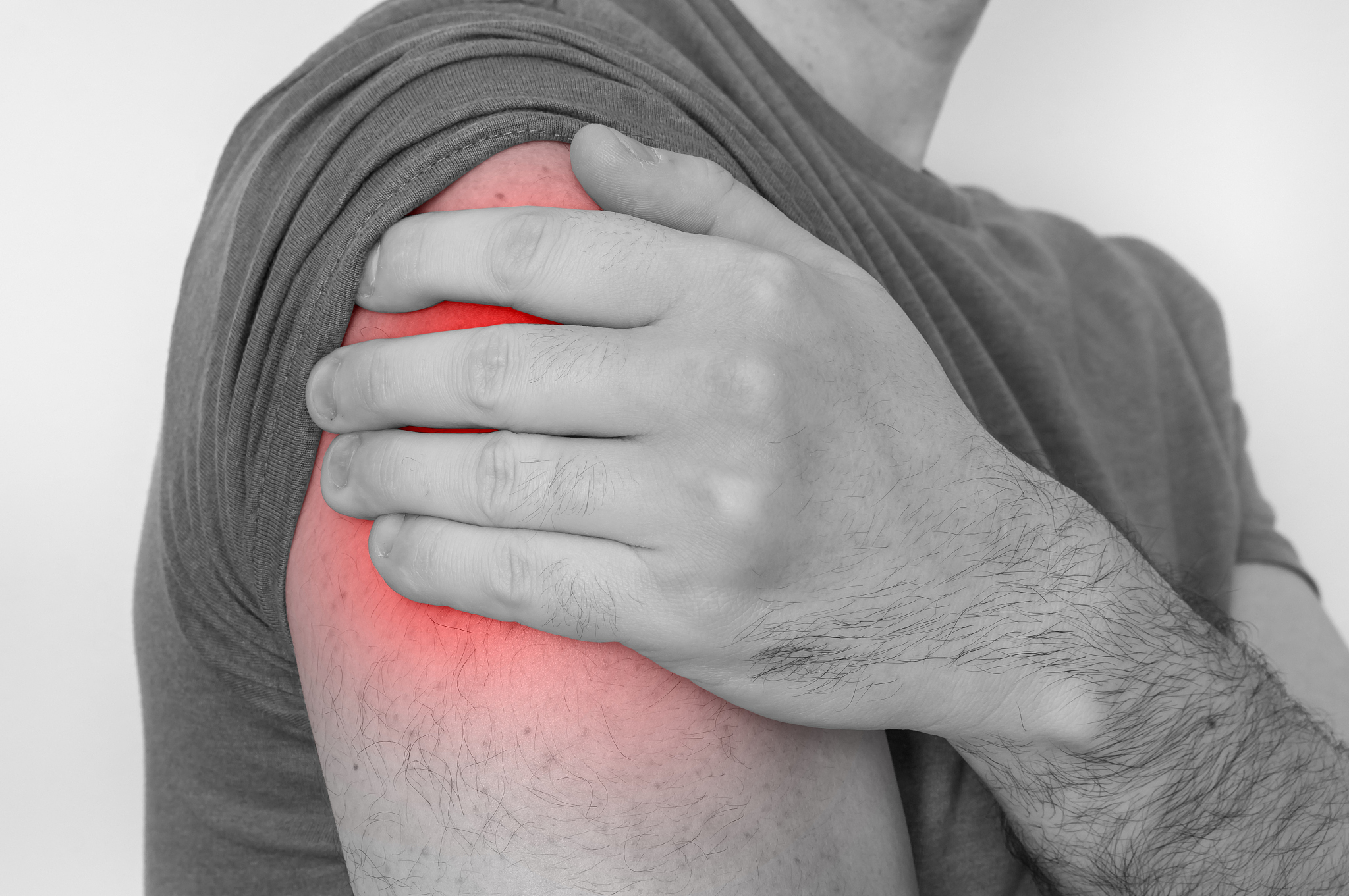 man with shoulder pain is holding his aching arm