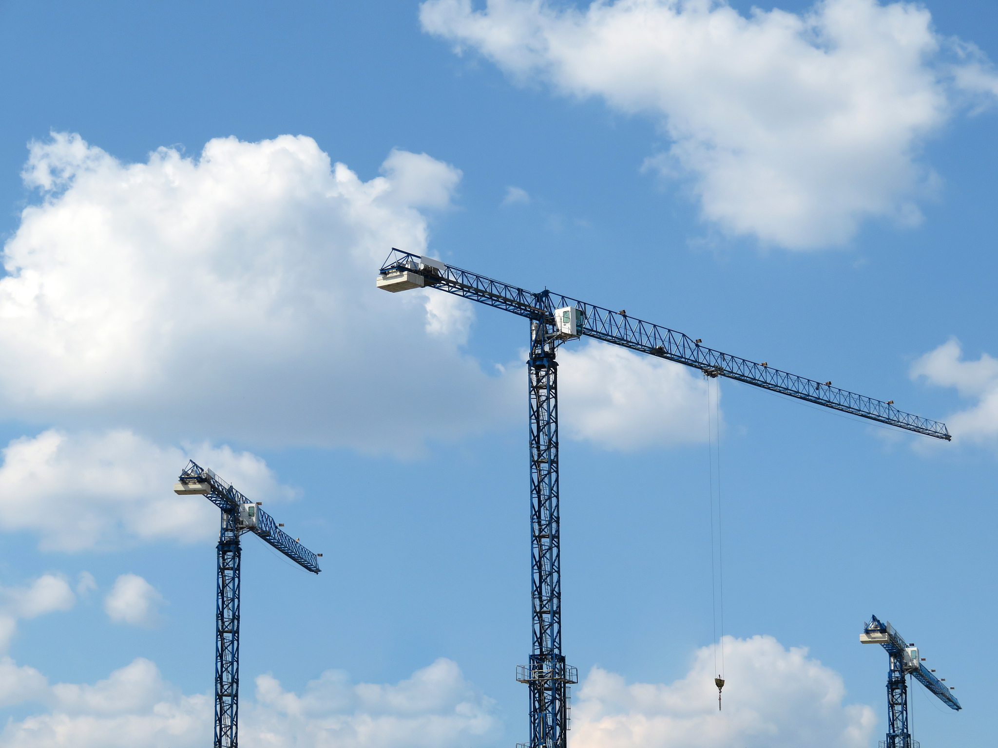 construction cranes on cloudy blue sky background