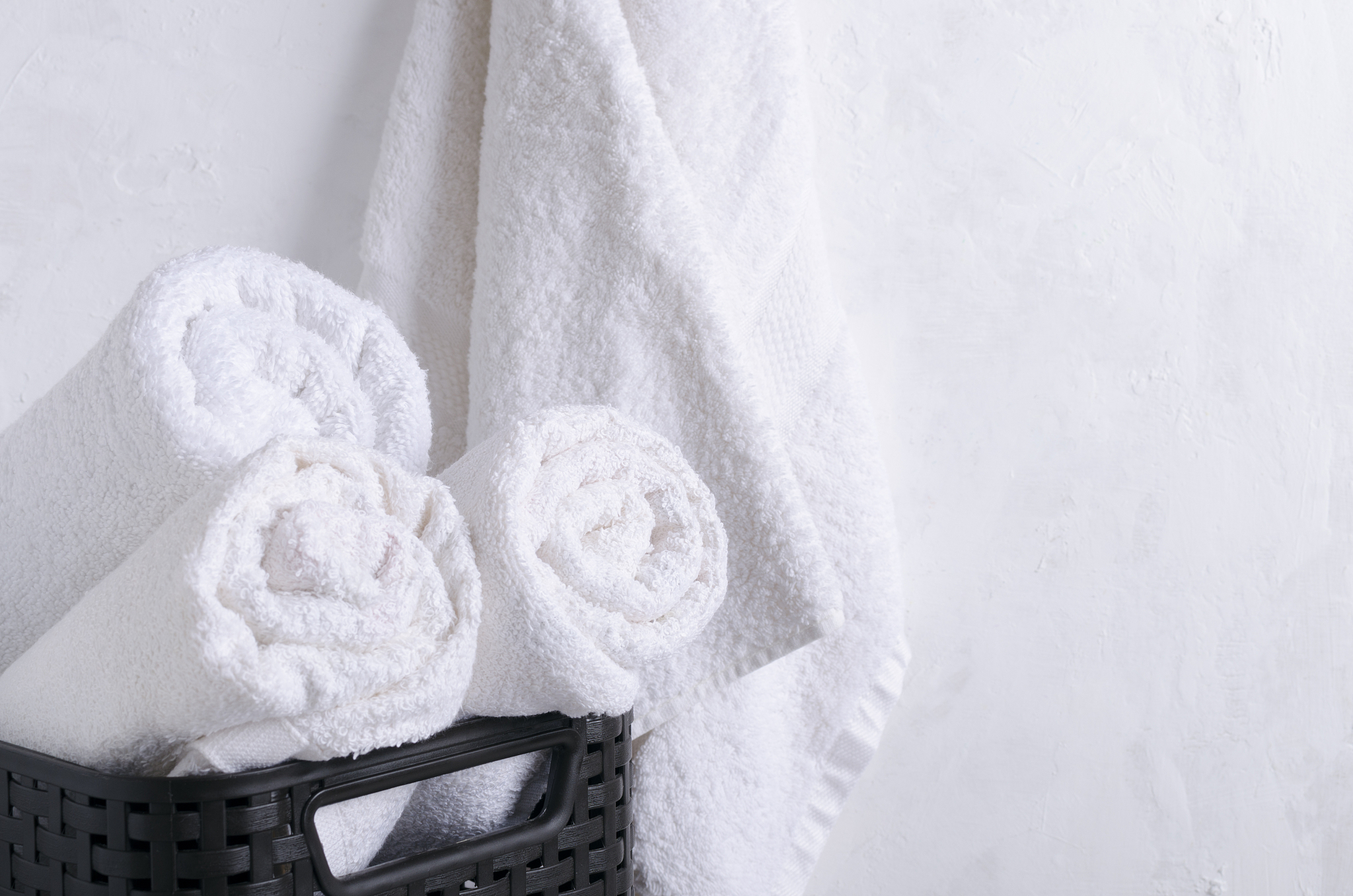 rolled fresh white towels in the basket,hanging towel against wh