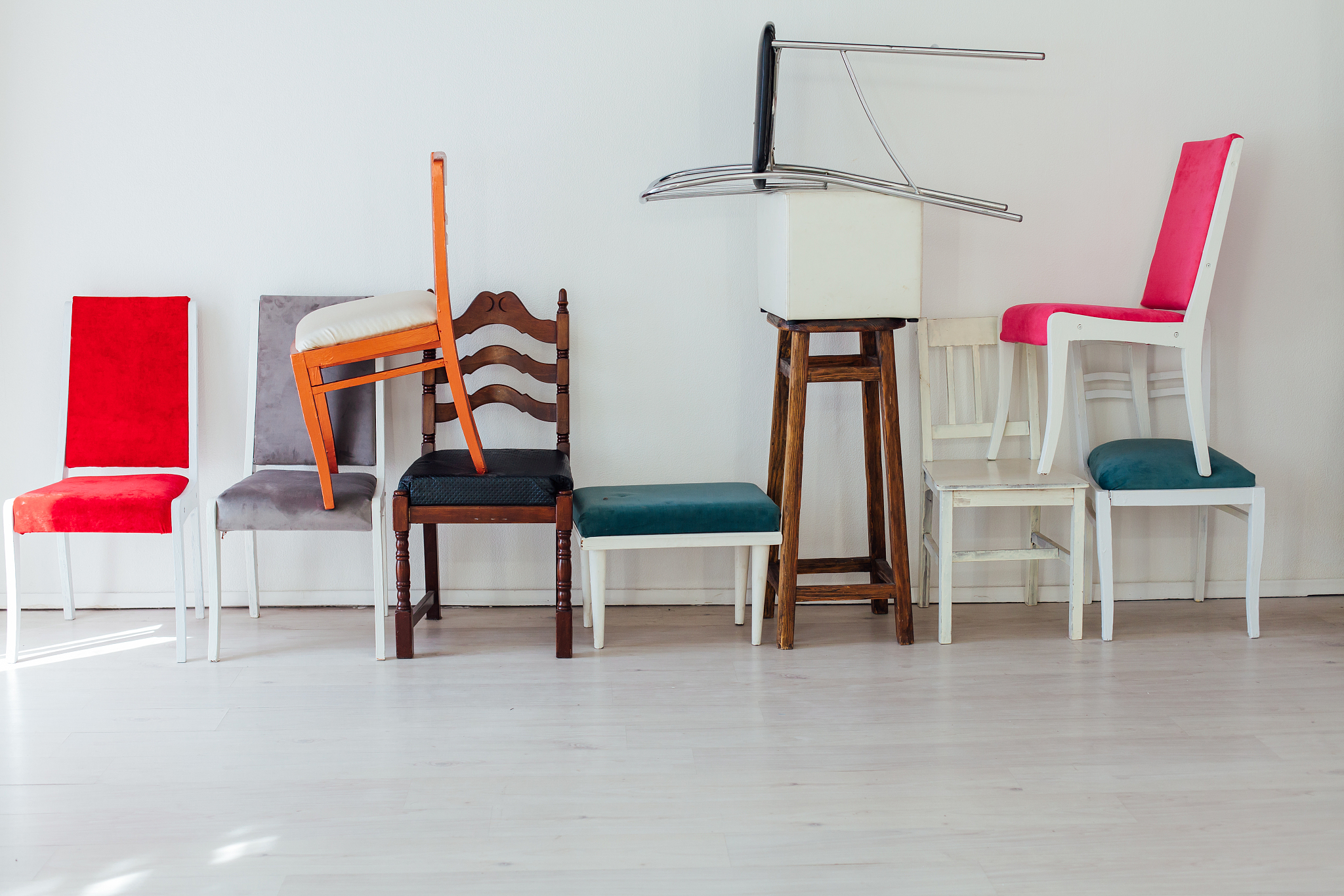 many different chairs of different colors stand at the white wal